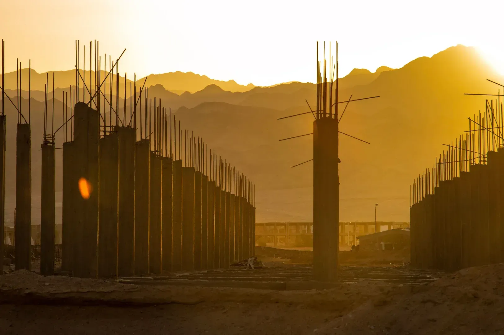 A scenic, golden-hour silhouette of structural pillars rising from a desert landscape, visually representing the metaphor of
