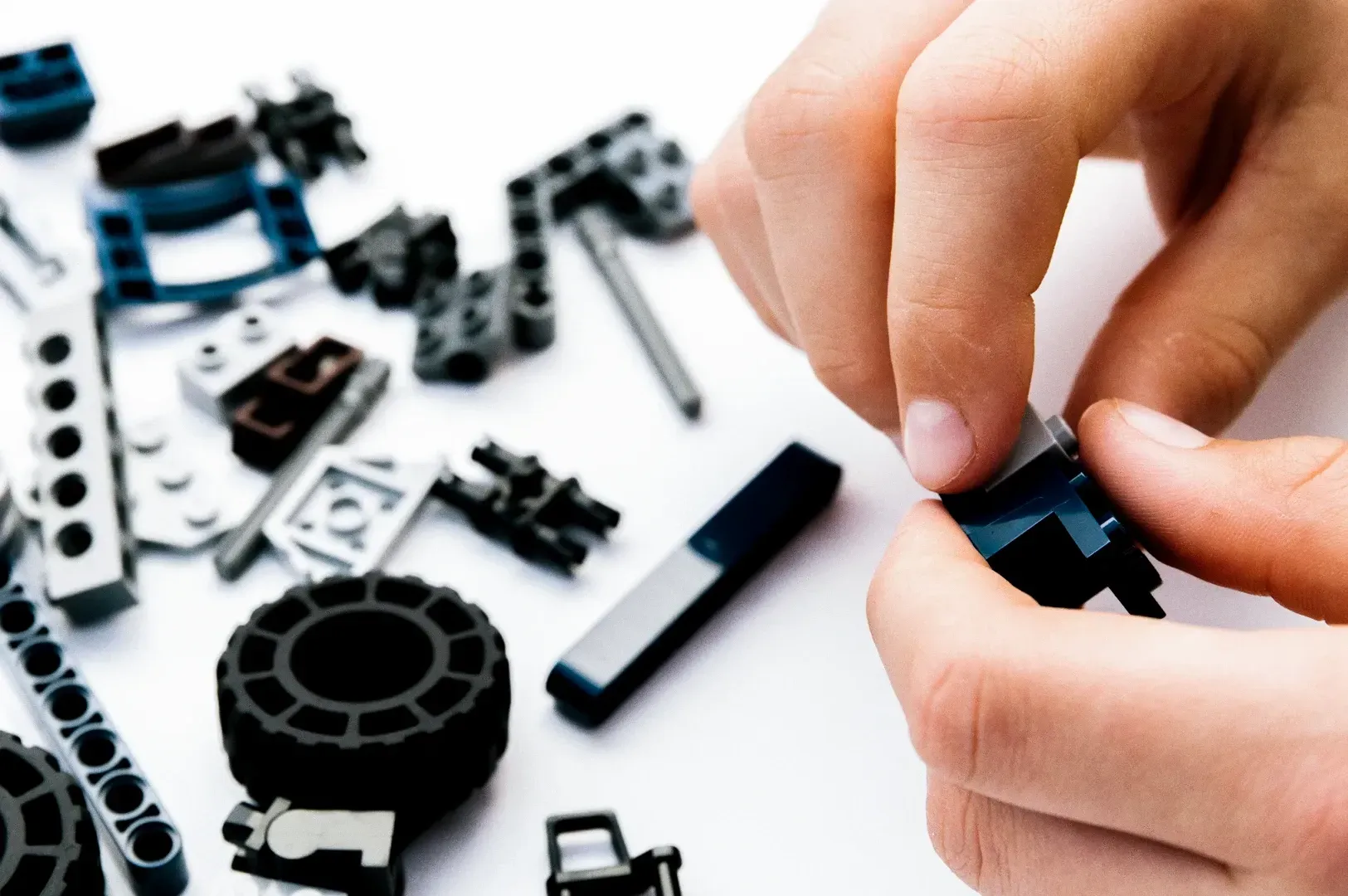 Close-up top-down shot of hands carefully assembling small mechanical components on a white surface, representing craftsmanship, focus, problem-solving, and mindful maintenance.