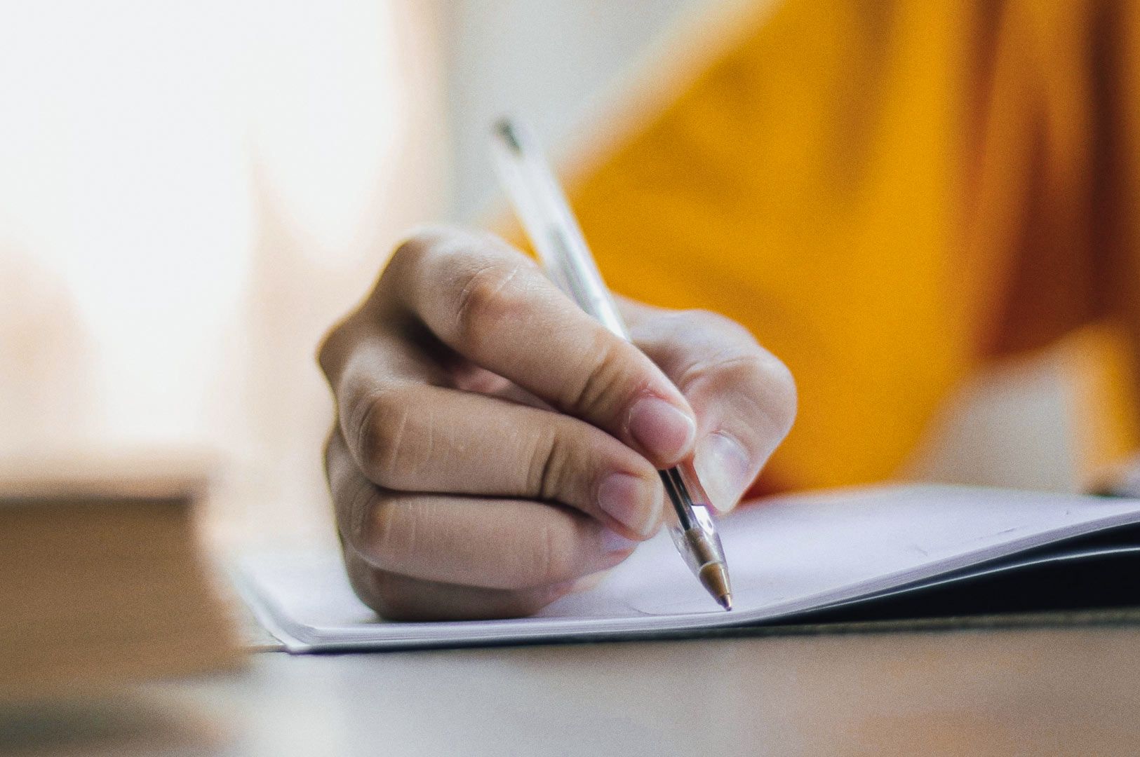 Close-up of person writing on paper indoors.