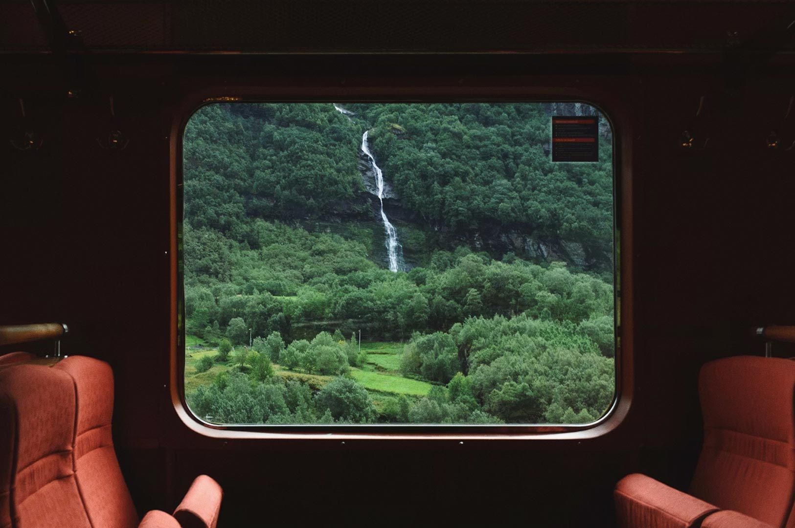 Waterfall and green forest landscape seen through a train window
