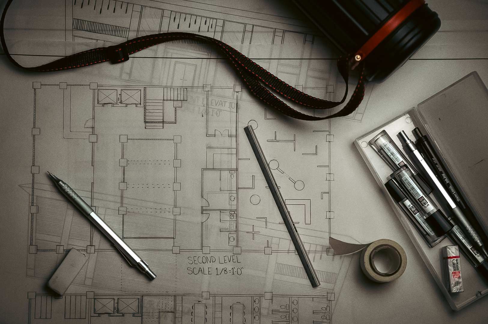 Architectural floor plan surrounded by drafting tools and drawing equipment.