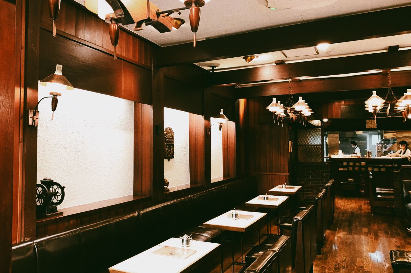 Cozy café interior with wooden walls and warm lighting.