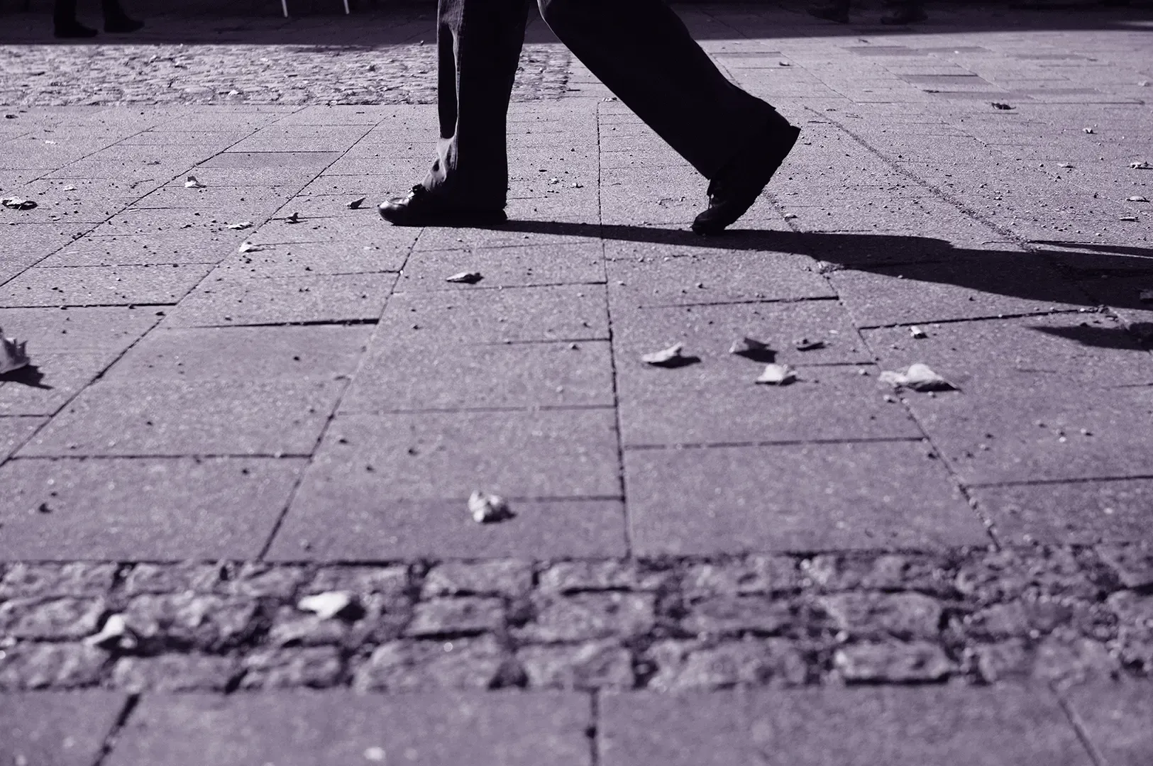 A candid moment of a person walking across a paved city street, symbolizing the literal and metaphorical journey of getting lost as a discipline.