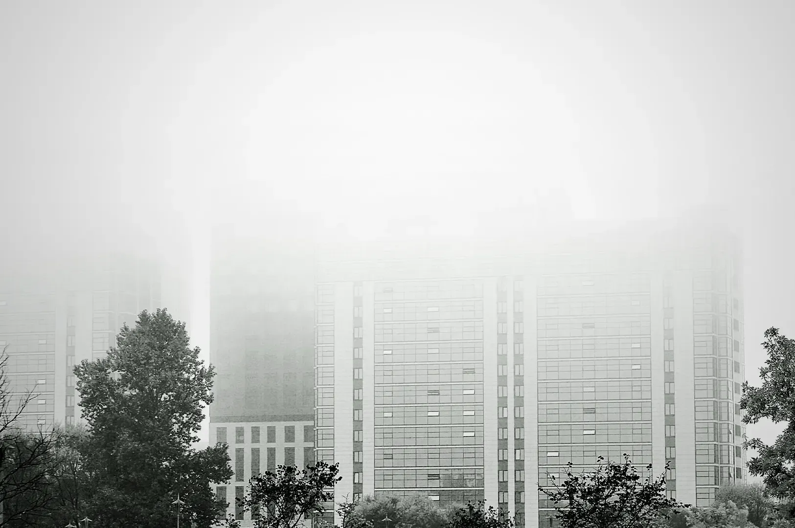 Buildings shrouded in thick, dense fog, capturing a surreal and obscured aesthetic, reminiscent of the dreamlike, conceptual urban landscapes described in Italo Calvino’s Invisible Cities.