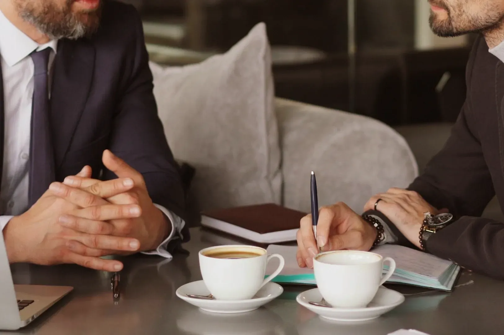 Two professionals engaged in a focused, face-to-face conversation over coffee, illustrating the power of presence, active listening, and the suspension of assumptions required for authentic dialogue between leaders and their teams.