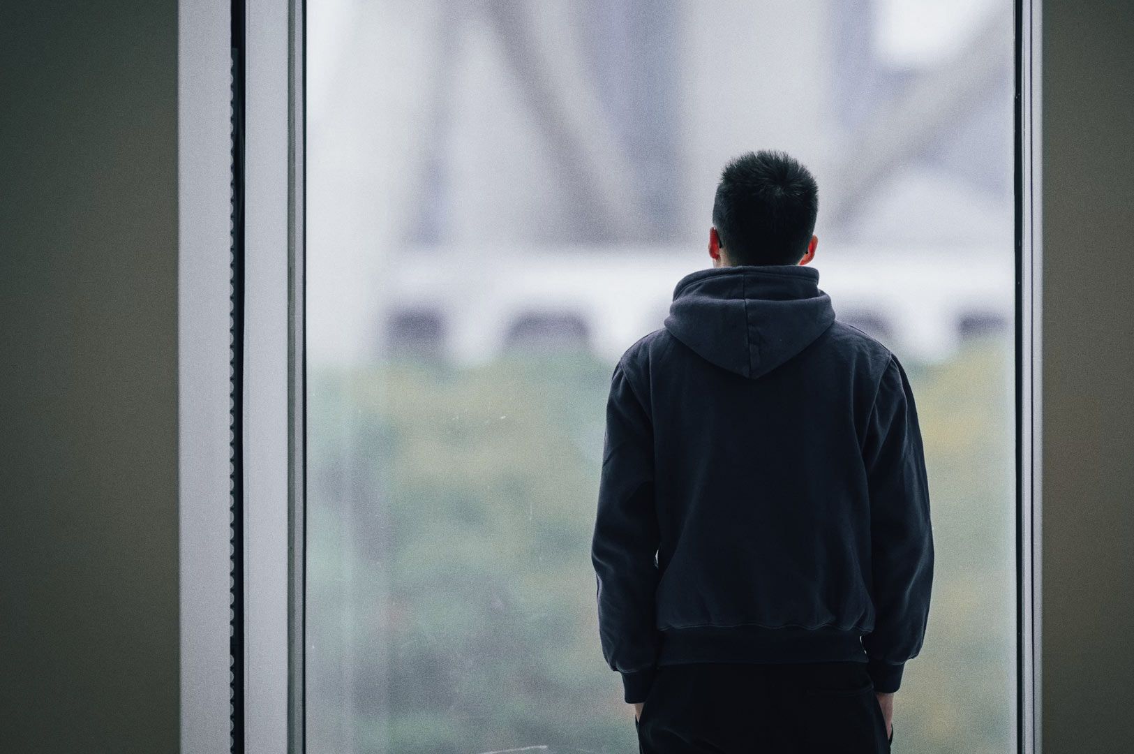 Indoor scene with contemplative figure by window.