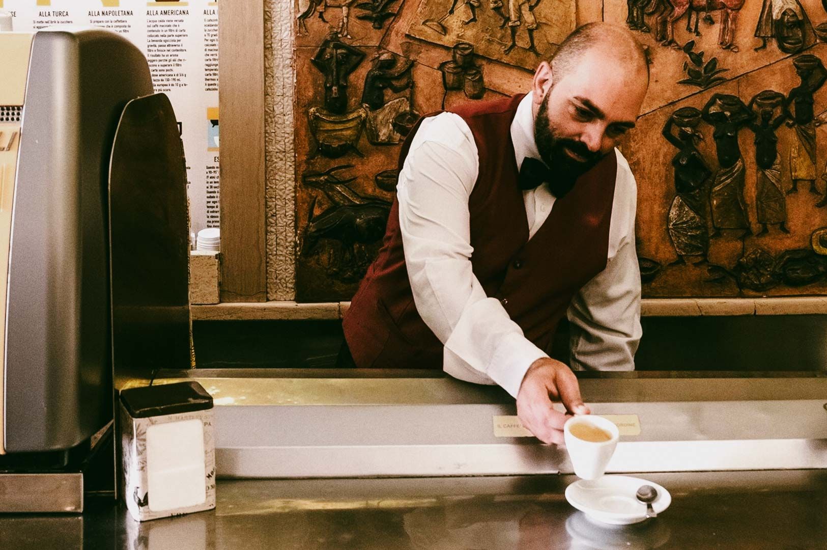 Barista serving a cup of coffee at an espresso counter.