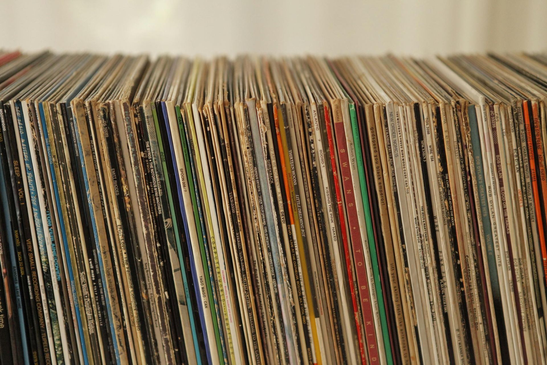 A large collection of vinyl record sleeves is packed tightly together, showcasing a diverse array of colorful spines and artist names. The viewpoint is a close-up that highlights the slight wear on the edges of the covers, suggesting a well-loved and extensive music library.