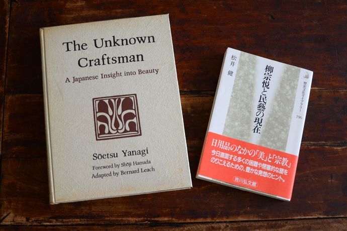 This overhead shot displays two books placed on a dark, weathered wooden table, featuring the Englis