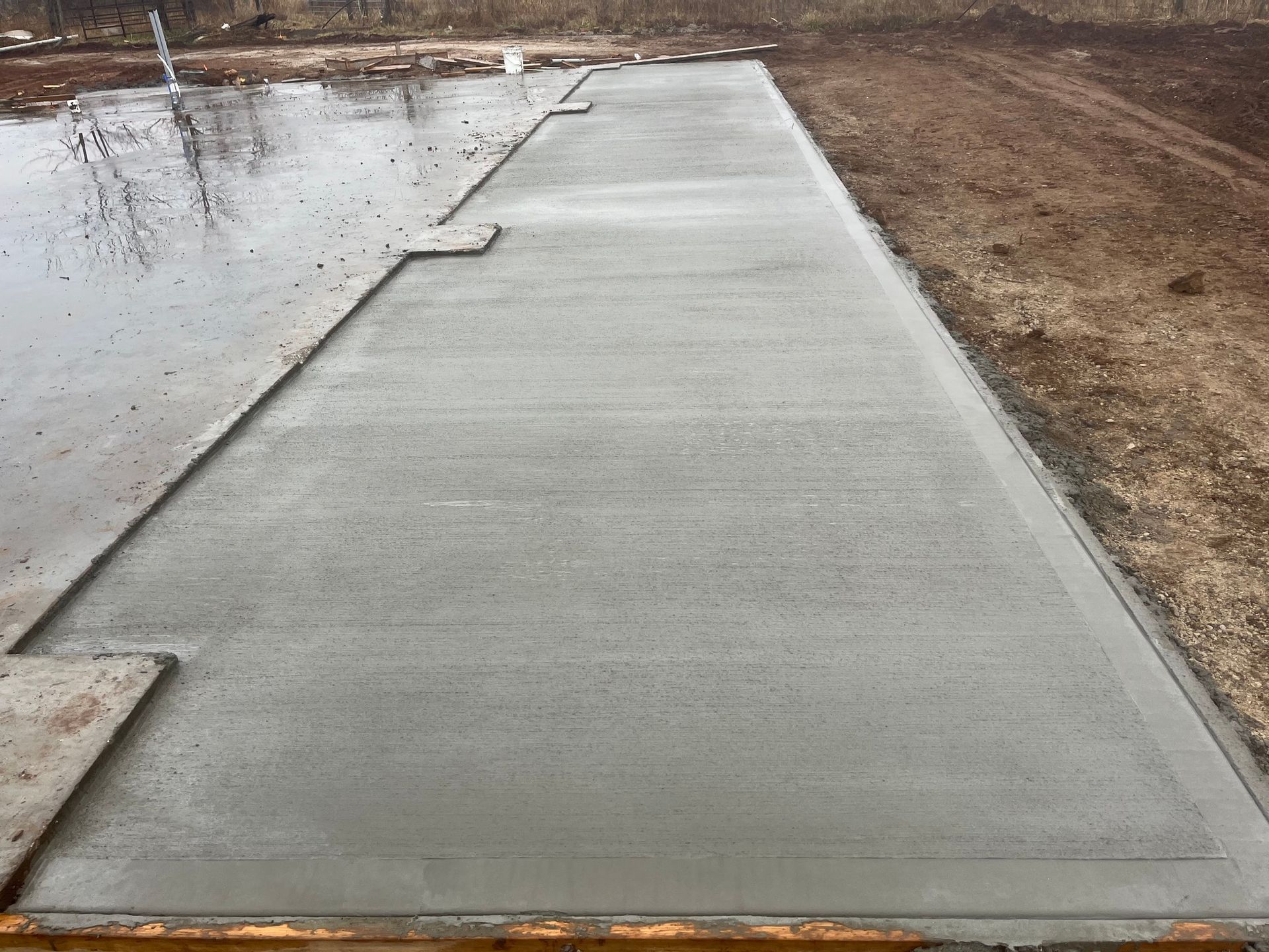 A concrete driveway is being built next to a body of water.
