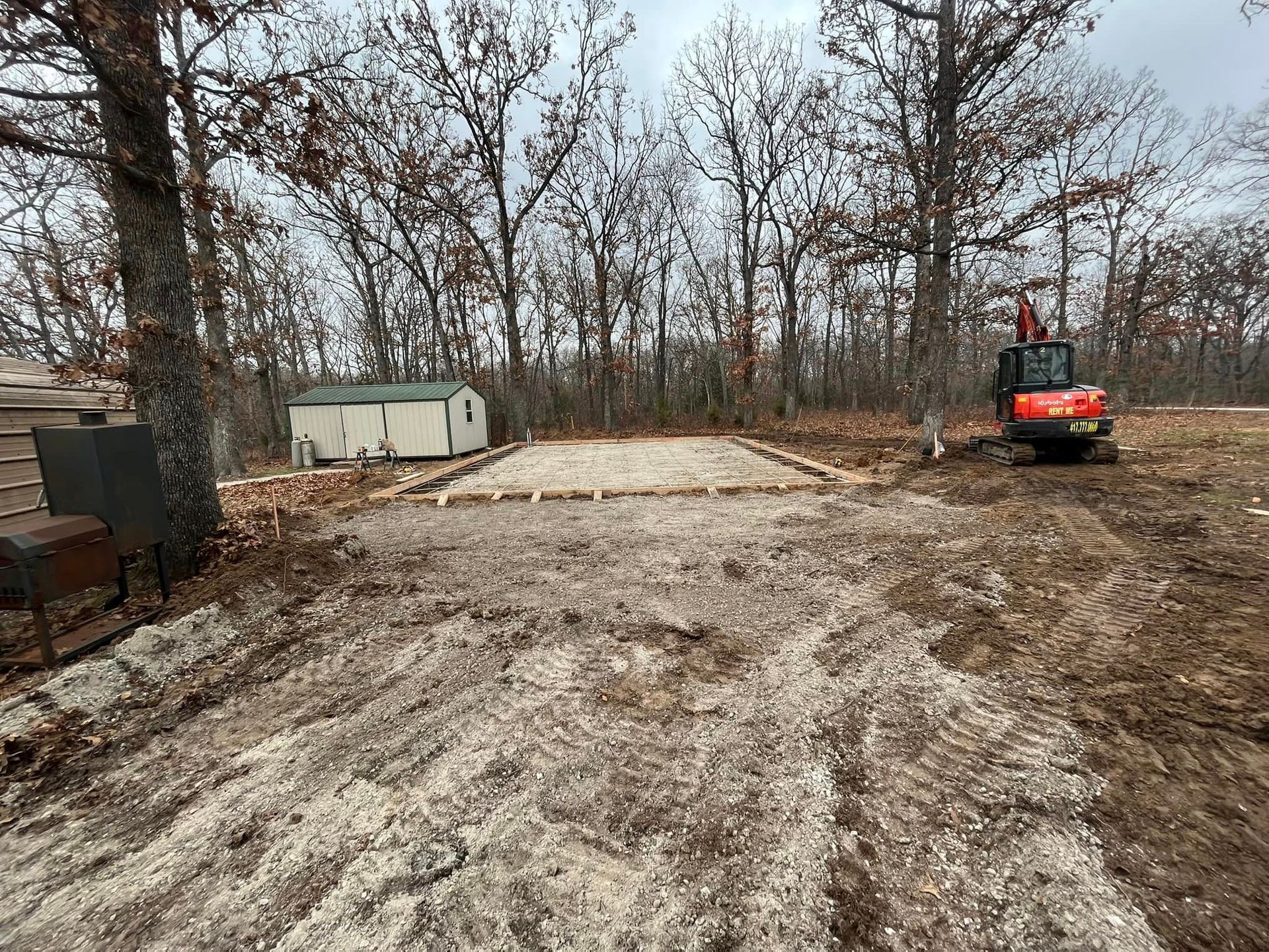 A red excavator is sitting in the middle of a dirt field.