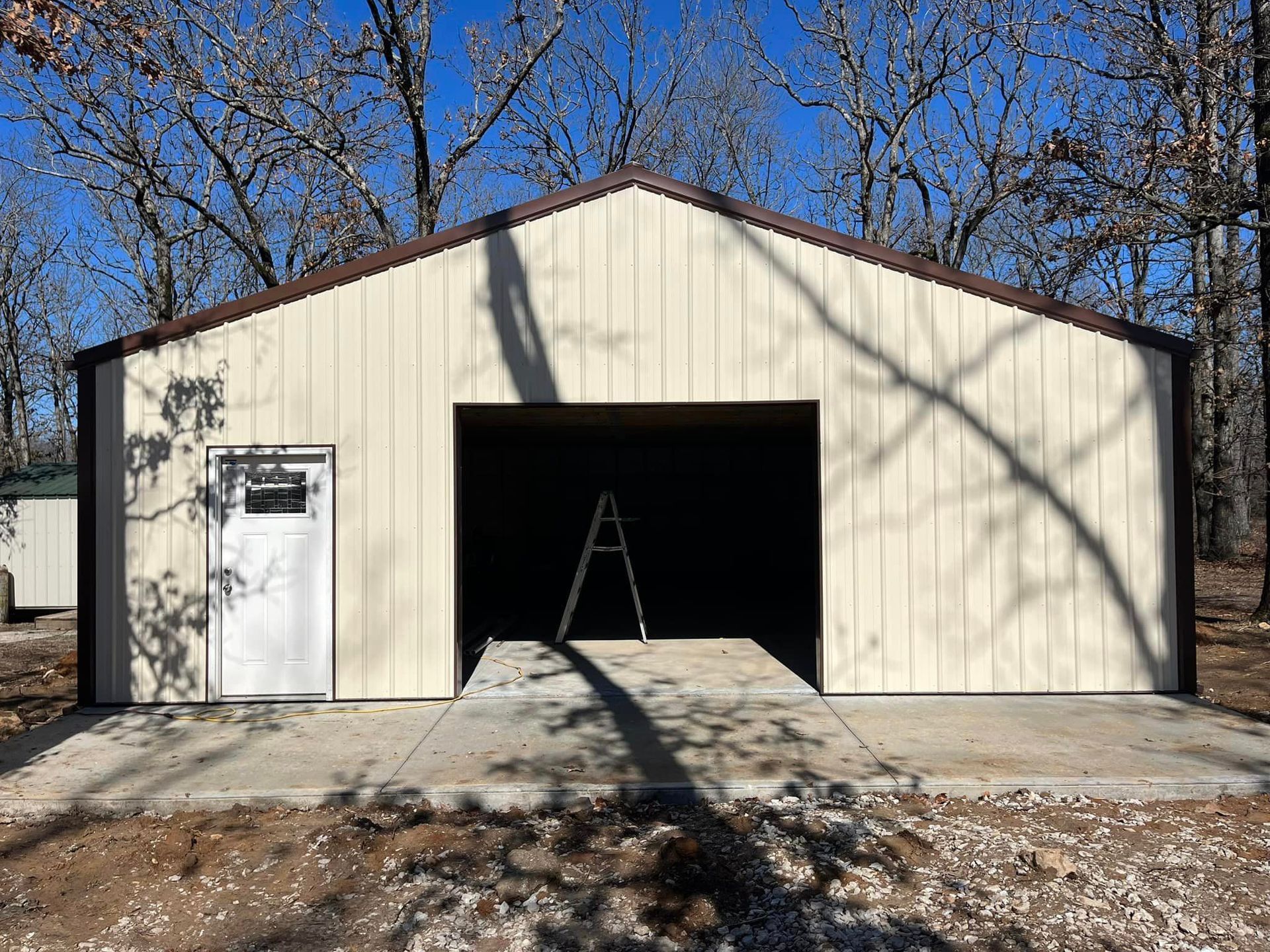 A large metal garage with a concrete driveway in front of it.