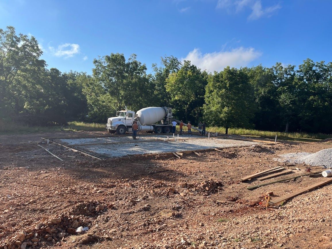 A concrete mixer truck is driving down a dirt road.