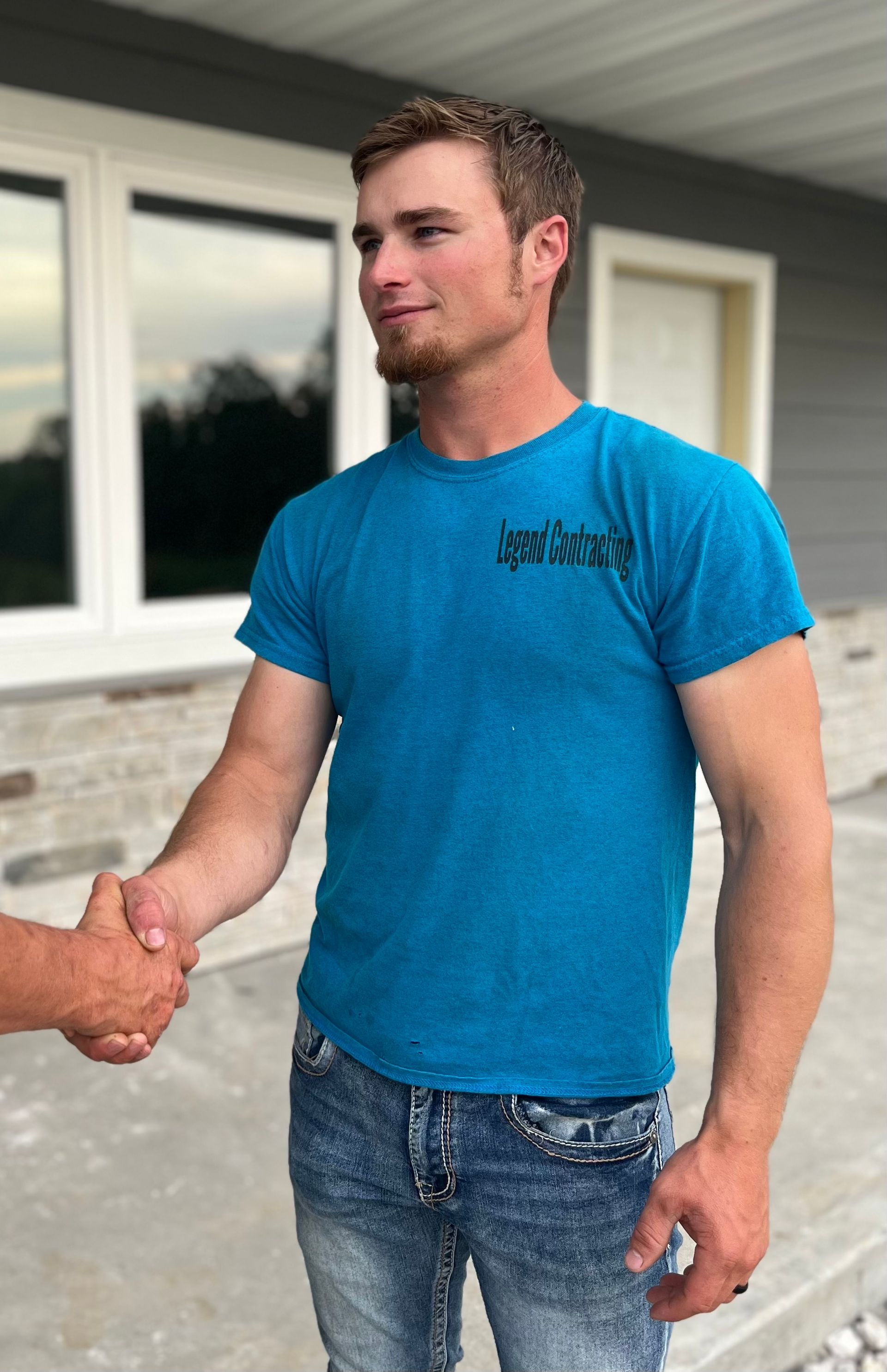 A man in a blue shirt is shaking hands with another man.