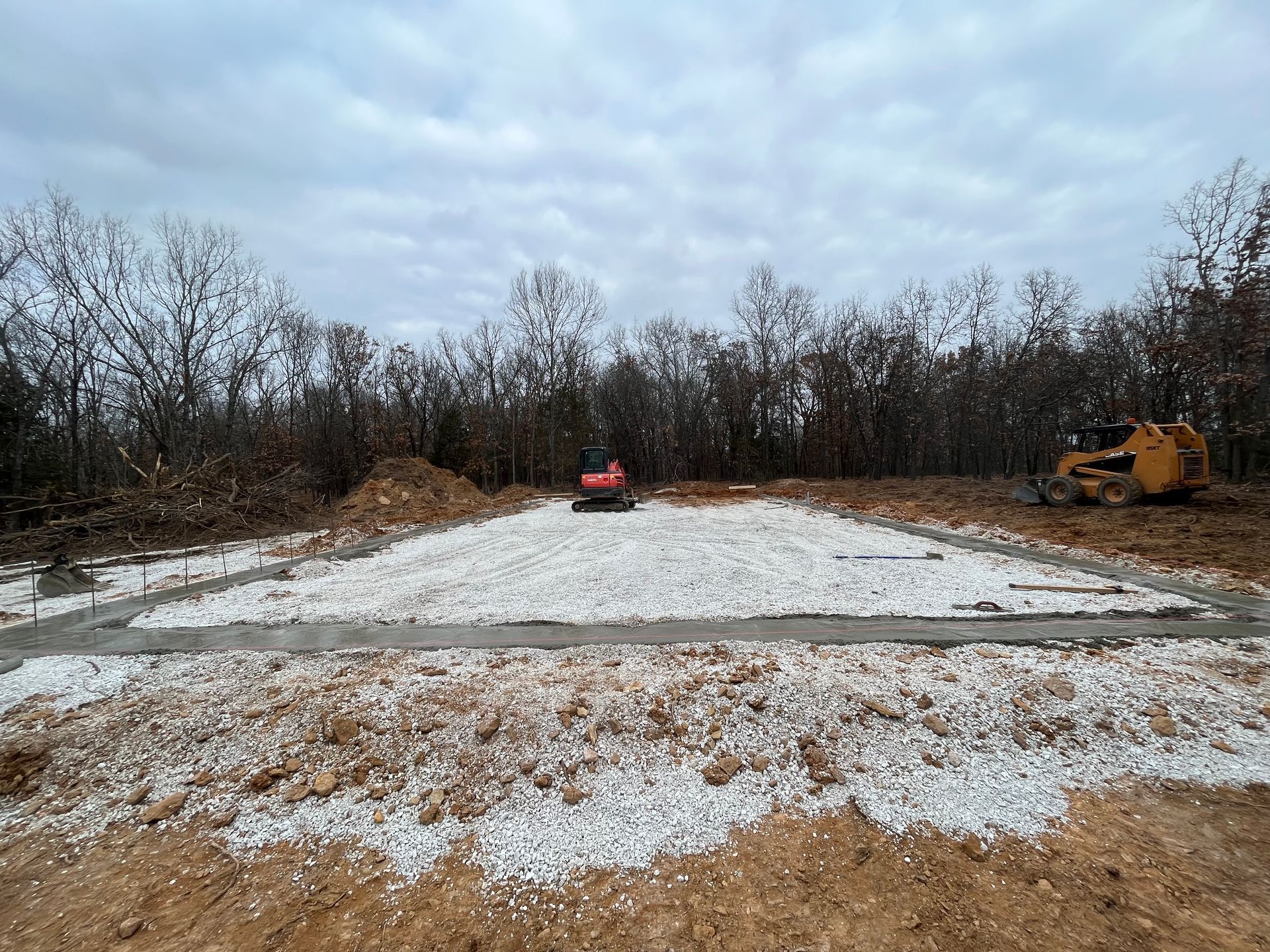 A construction site with a lot of dirt and trees in the background.