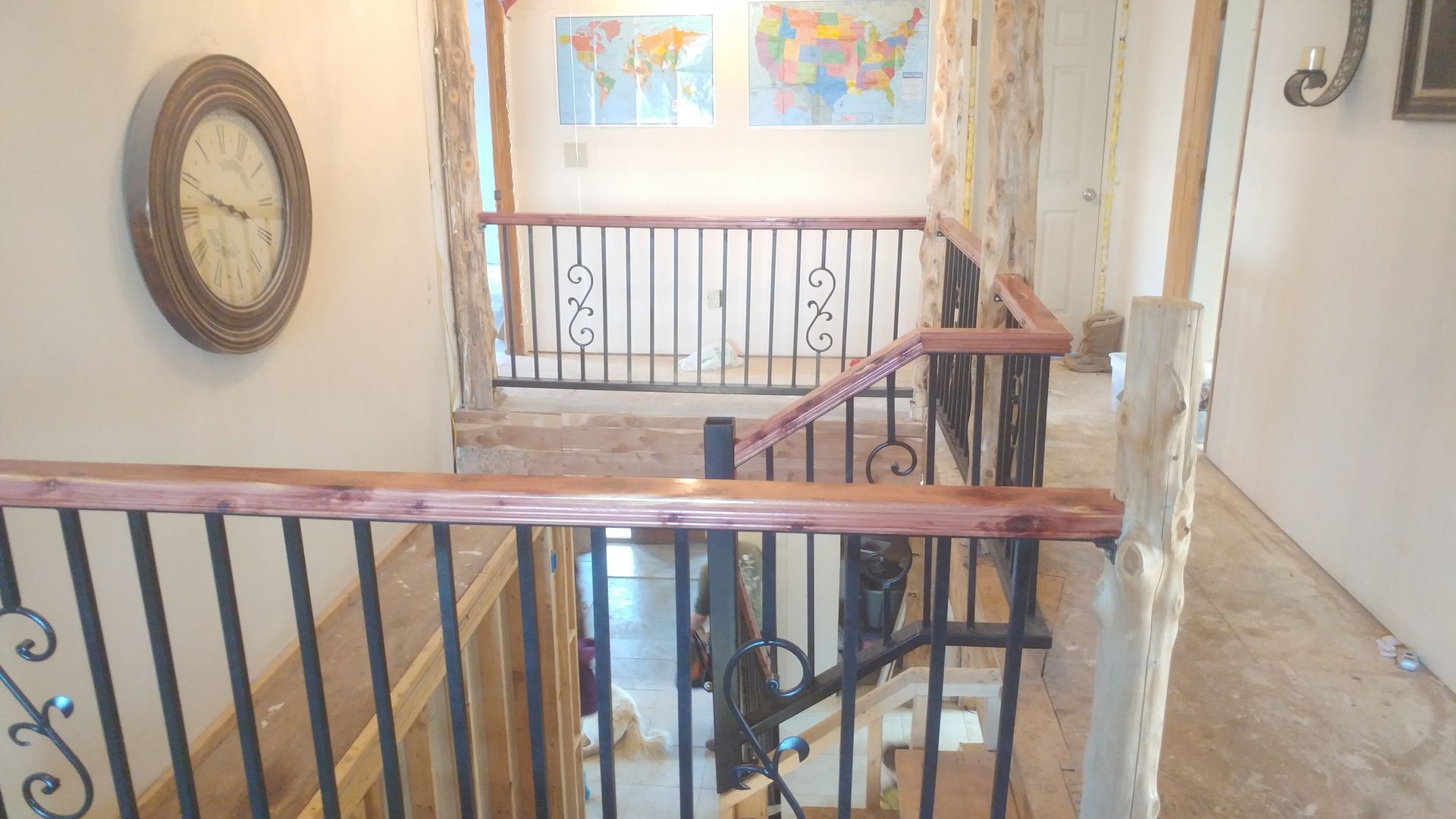 There is a clock on the wall above the stairs.