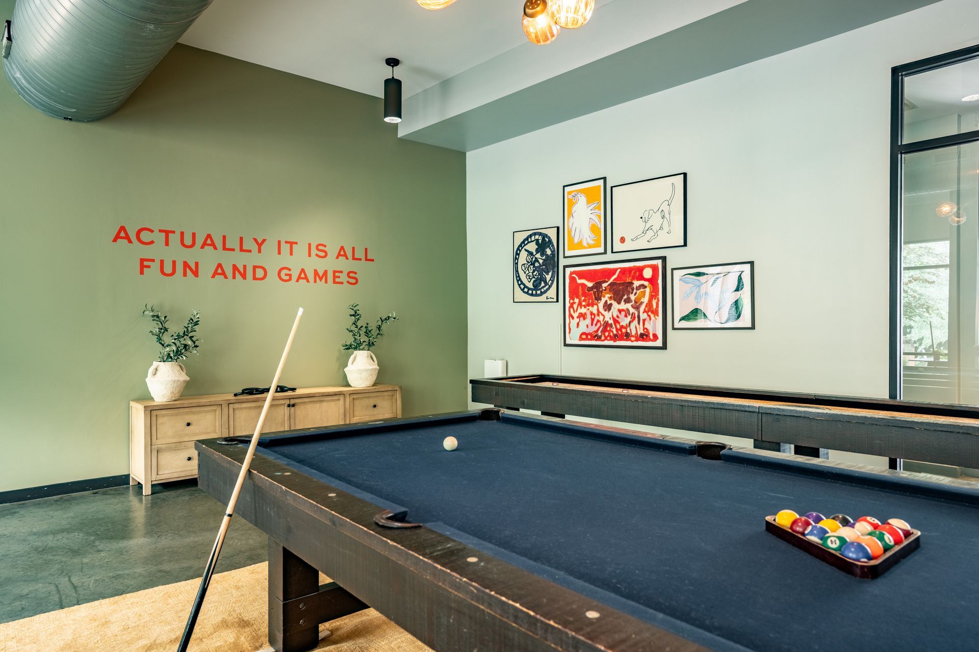 Pool table in a game room with art on the wall and text 