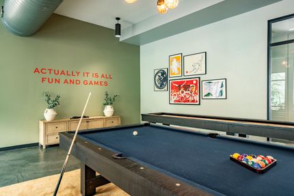 A patio with tables and chairs and a neon sign that says bang