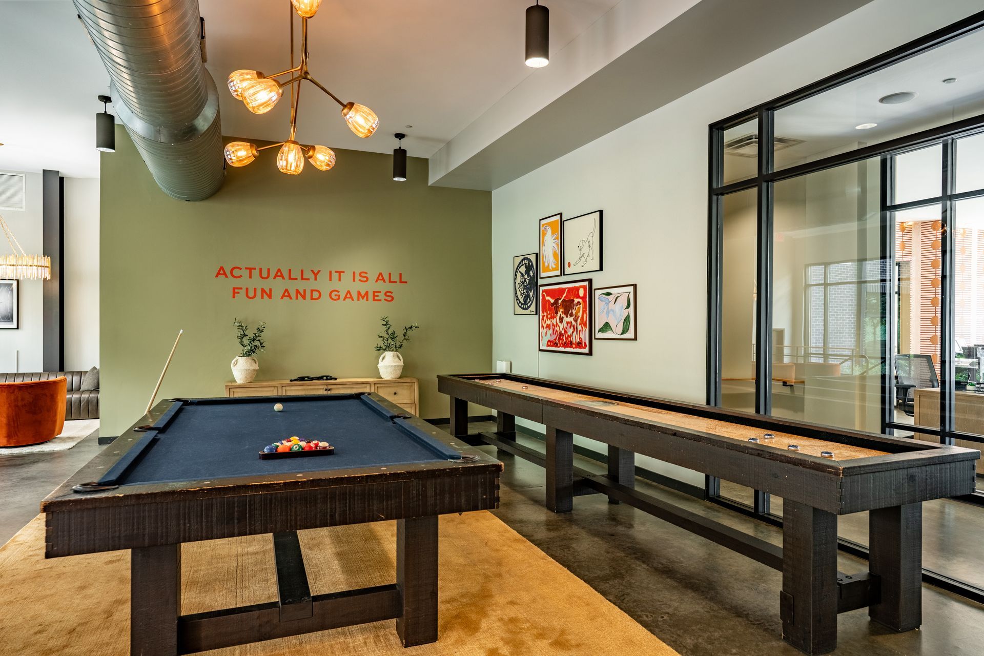 Game room with a pool table, shuffleboard, and a wall with a quote in red text.