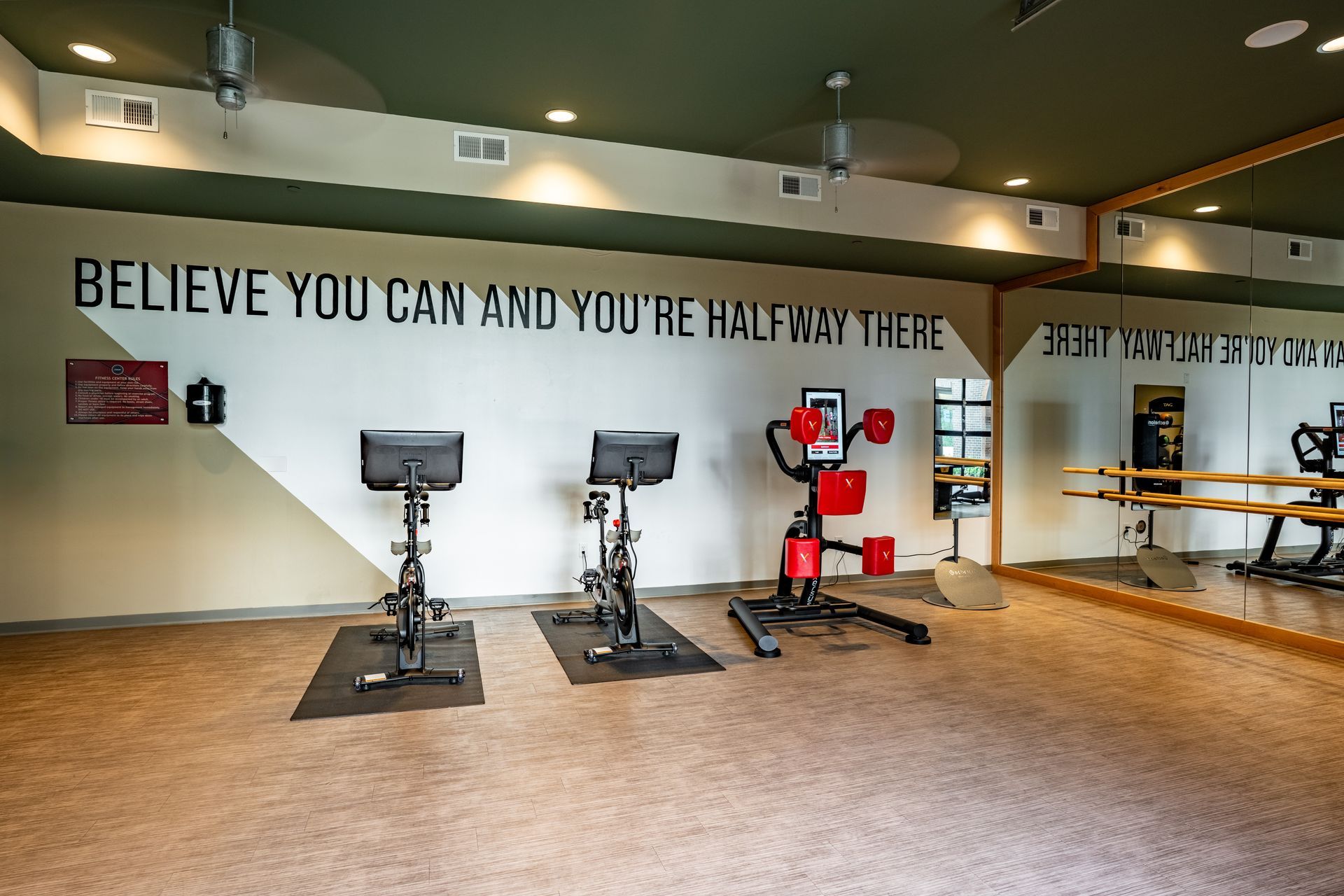 Gym interior with stationary bikes, punching bag, and mirror.