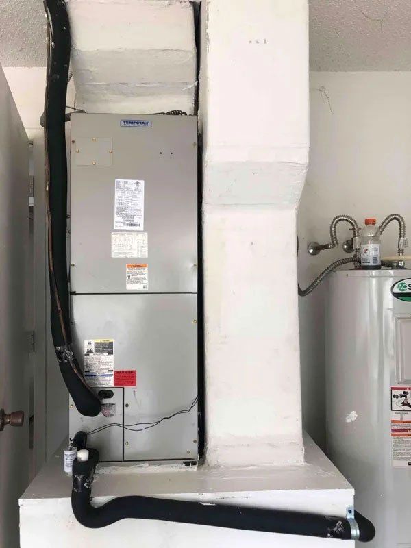 A water heater is sitting next to a heater in a room.