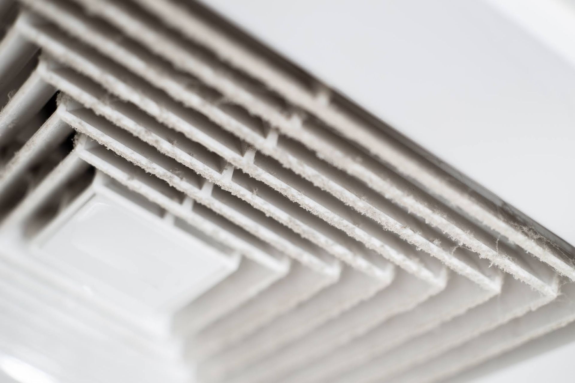 A close up of a white air vent on a ceiling.