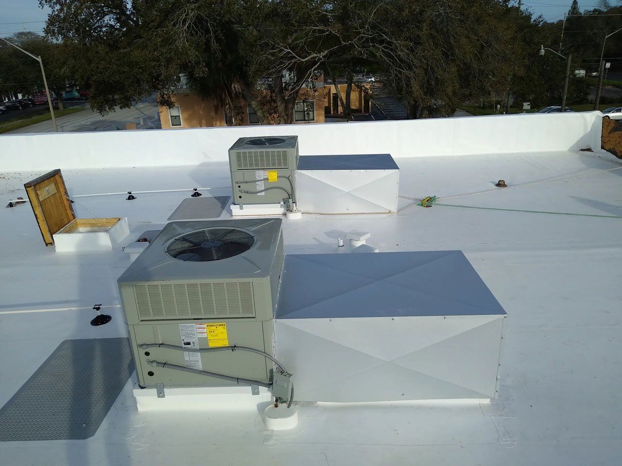 Three air conditioners are sitting on top of a white roof.
