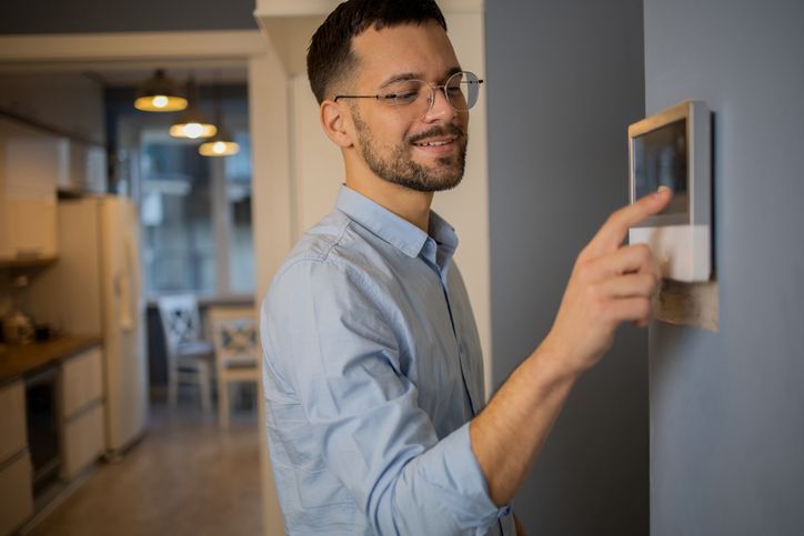 A man is pressing a button on a wall.