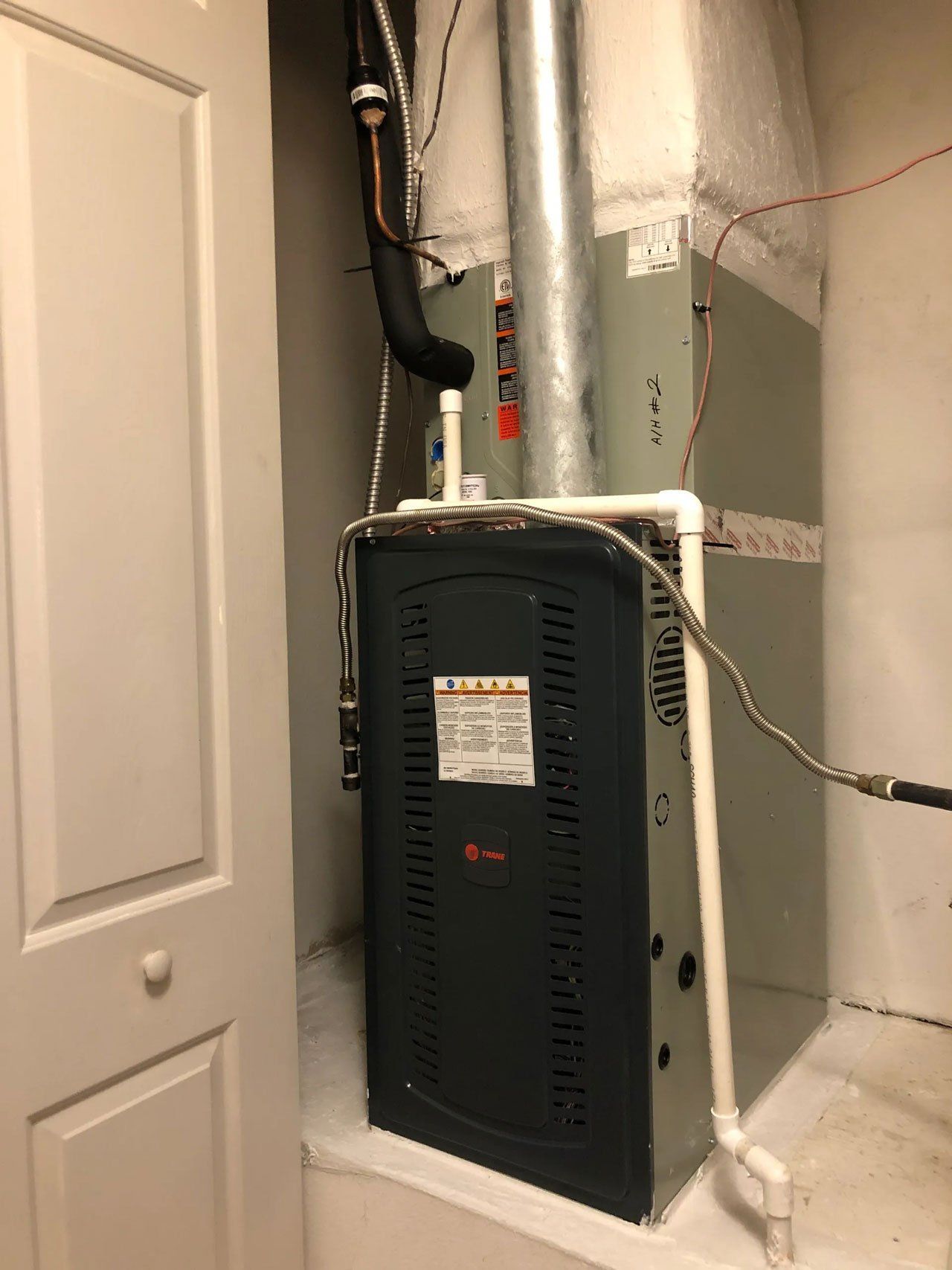 A furnace is sitting in a closet next to a door.