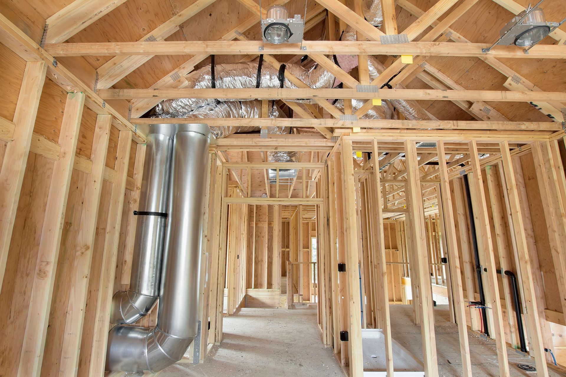 A house is being built with a lot of wood and metal pipes coming out of the ceiling.