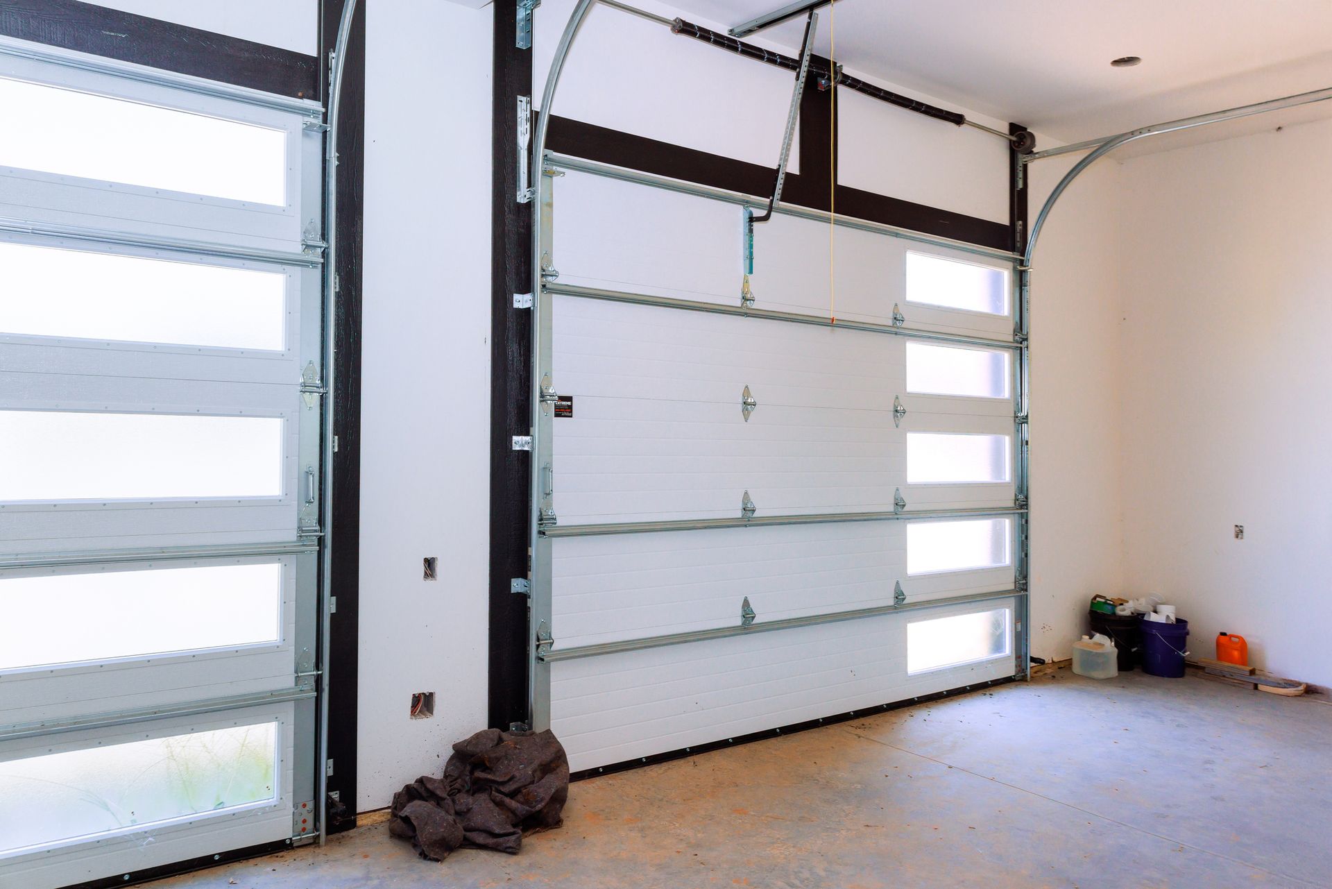 Garage interior with white doors and windows; concrete floor.
