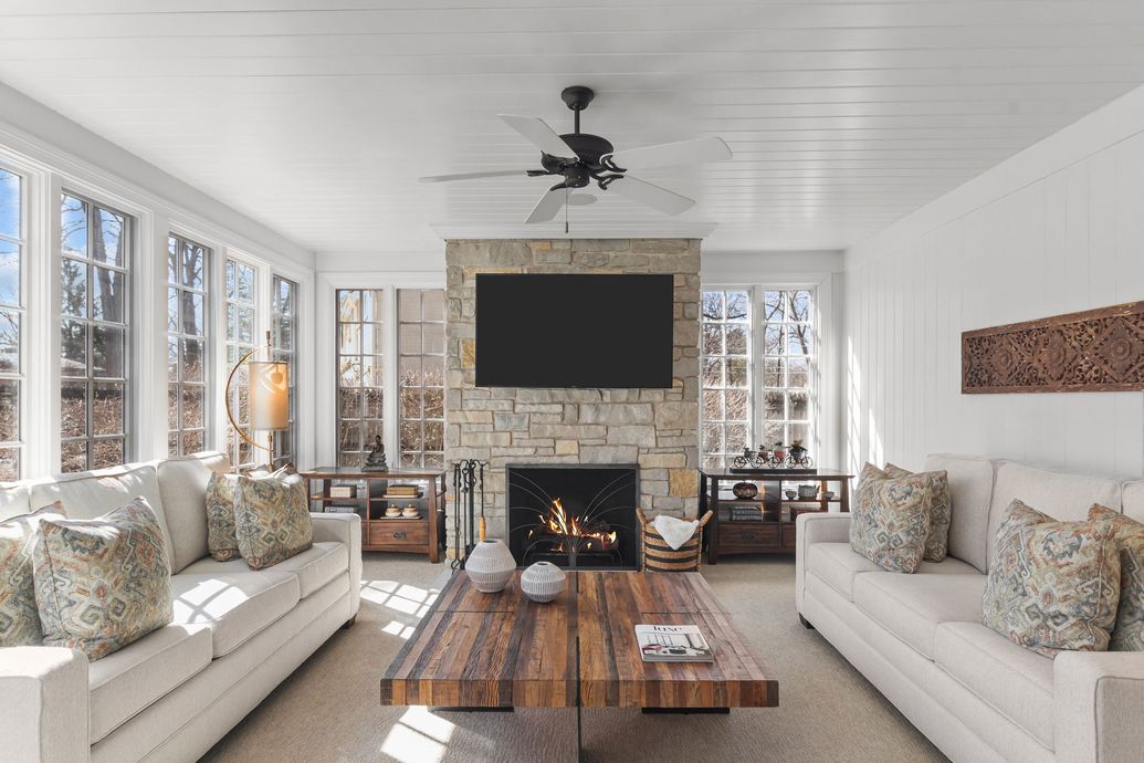 A row of suburban homes with light-colored siding, dark shingled roofs, small front yards, and paved driveways.