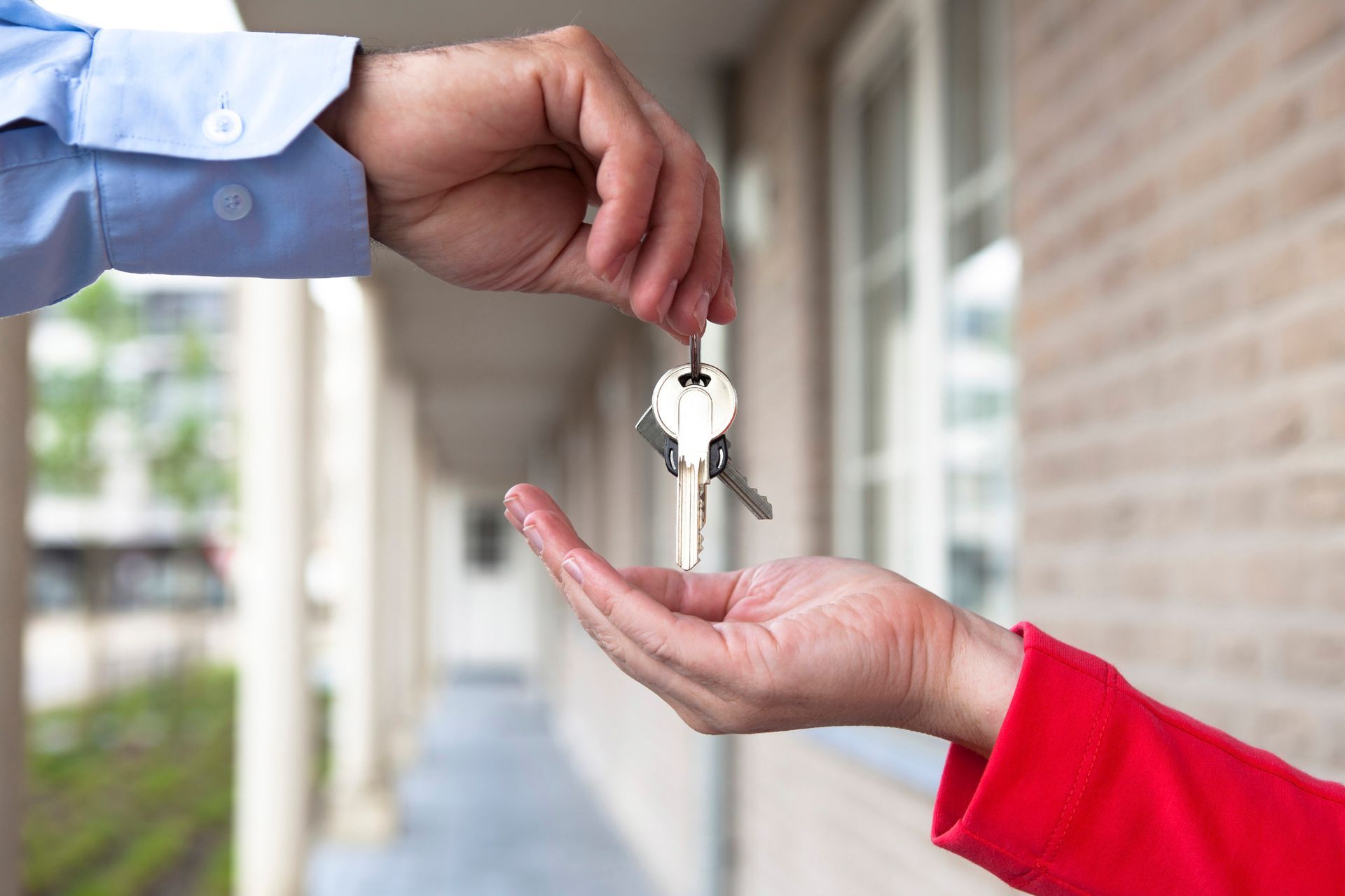 A street of traditional brick and siding homes in a quiet residential neighborhood on a sunny day with green trees.