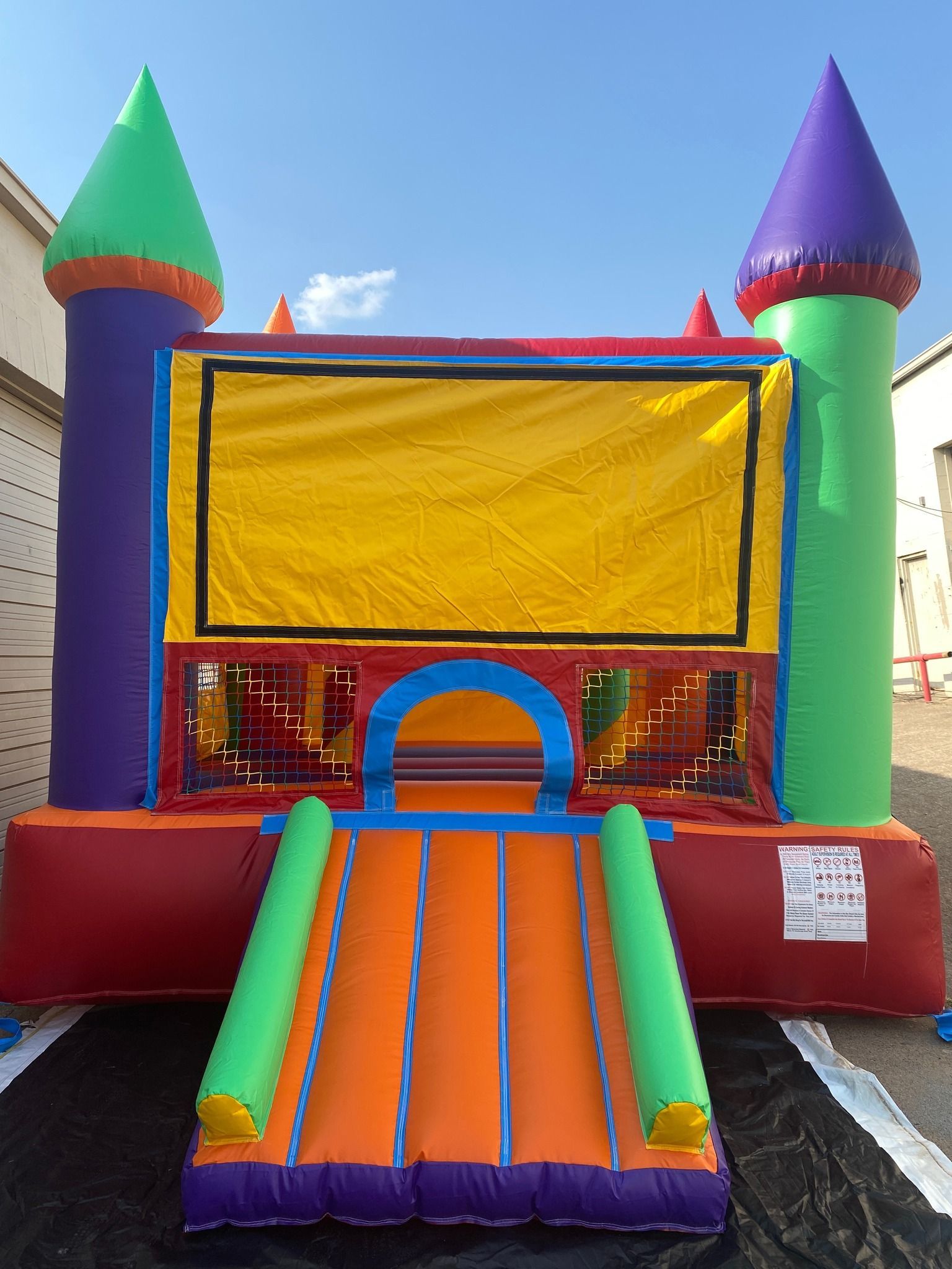 A colorful bouncy castle is sitting in a parking lot.