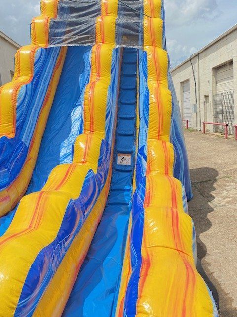 A blue and yellow inflatable water slide is sitting in front of a building.
