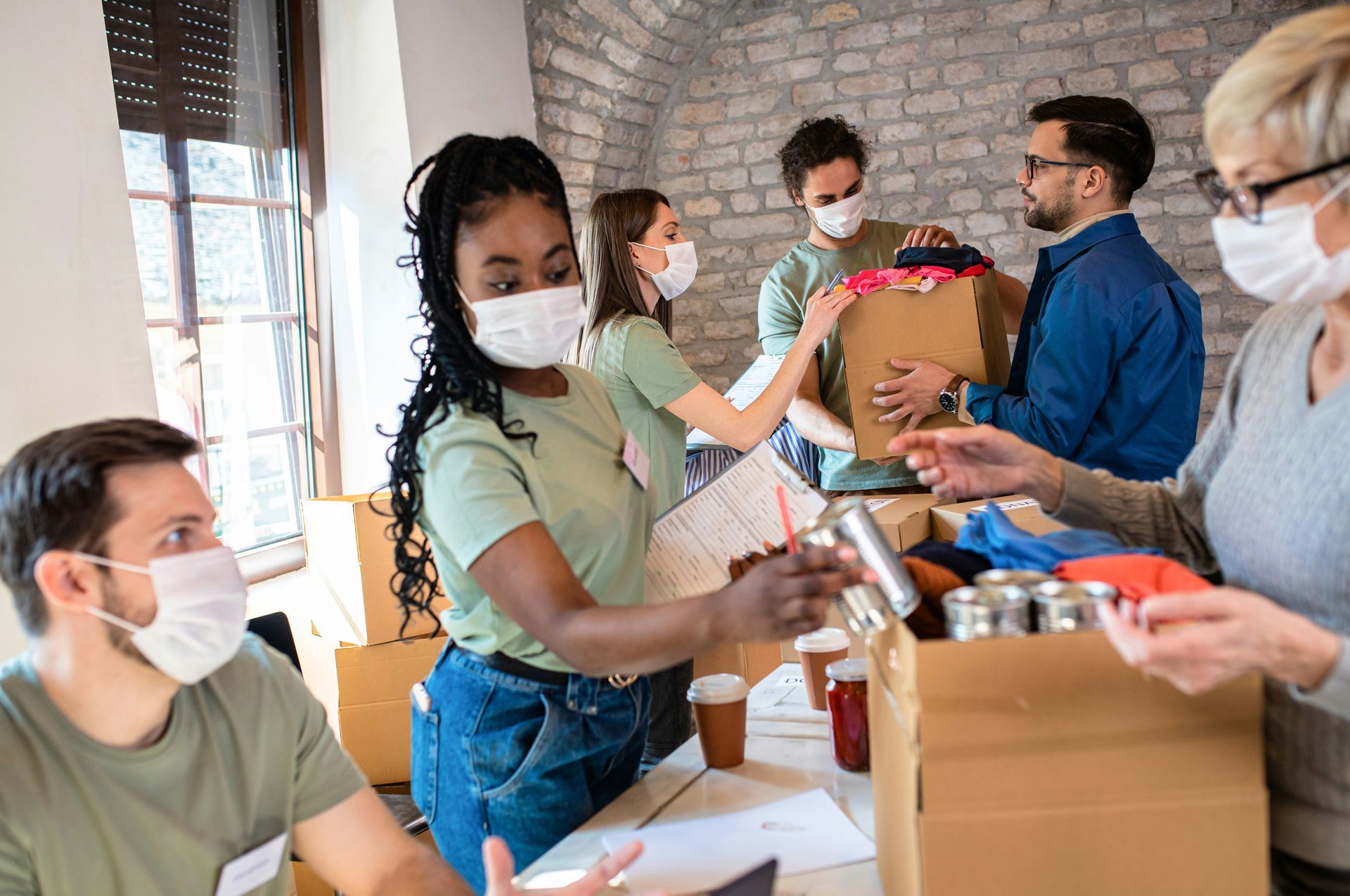 A group of people wearing face masks are gathered around a table.