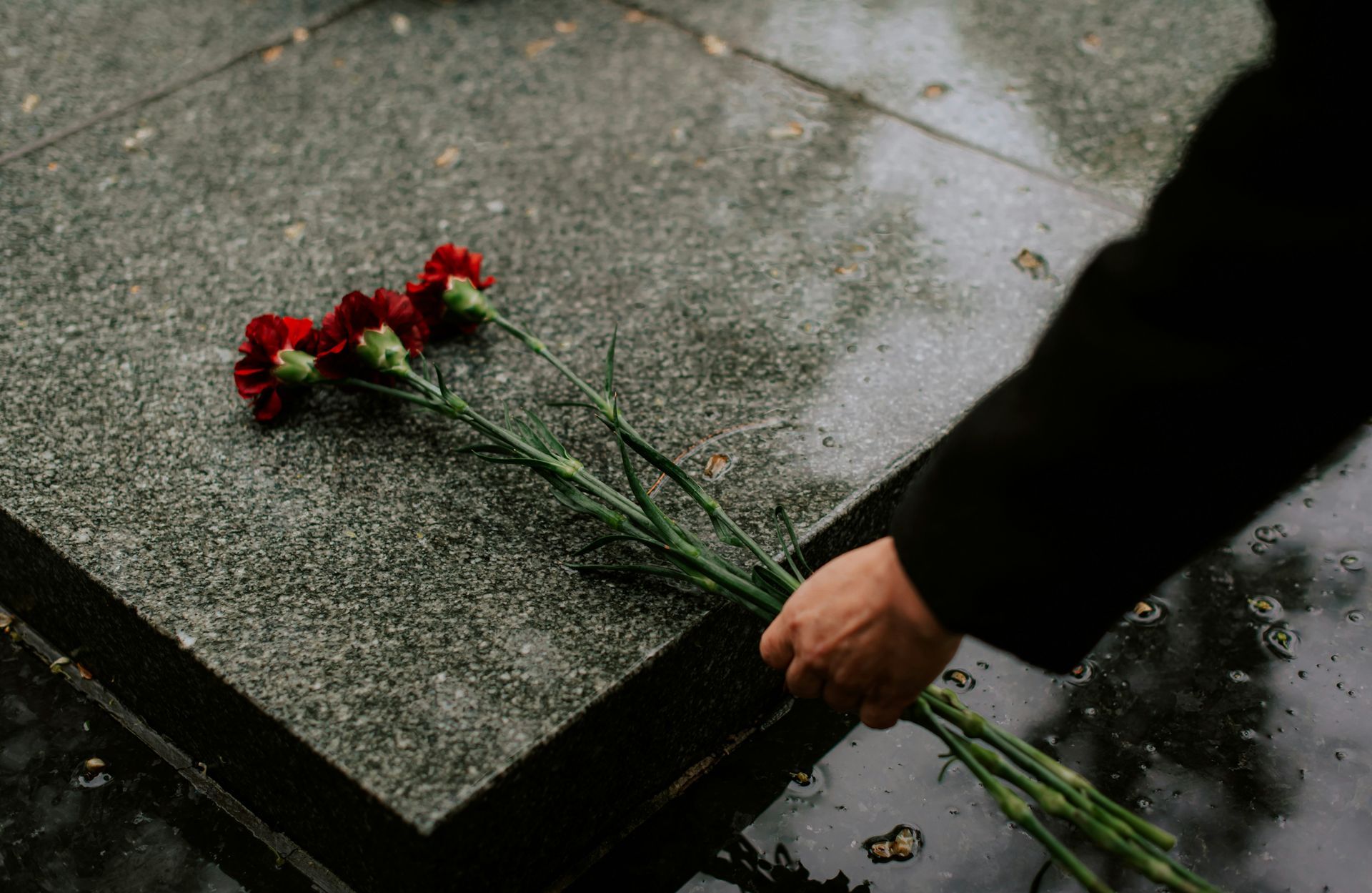 A person is putting flowers on a grave.