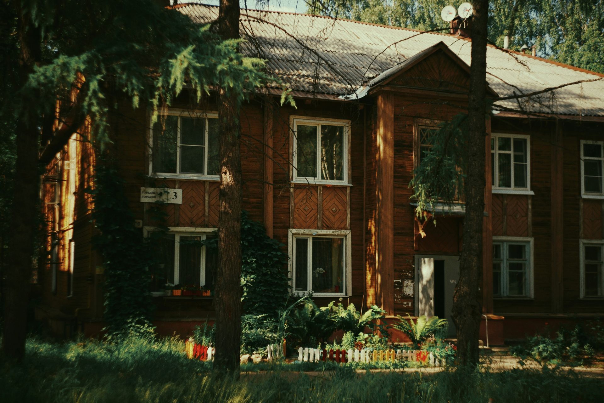A brick building with a lot of windows is surrounded by trees.