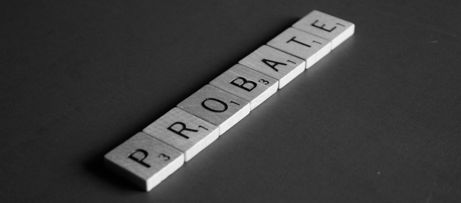 A black and white photo of scrabble tiles spelling out the word probate.