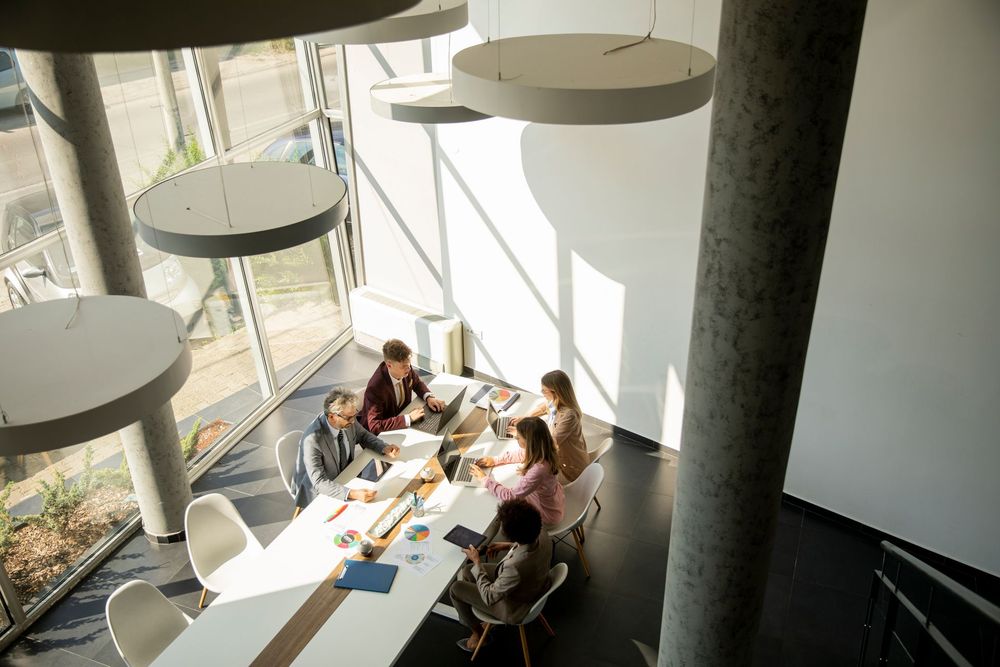 A group of people are sitting around a long table in a conference room.