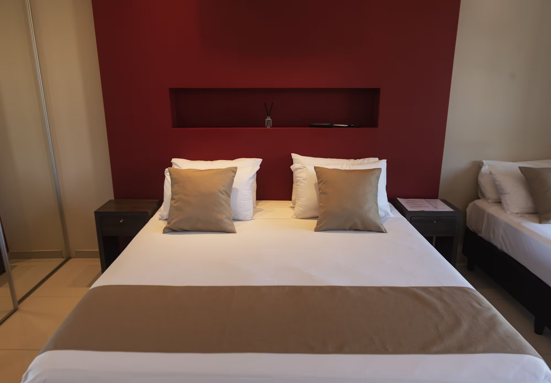 A hotel room with two beds and a red wall