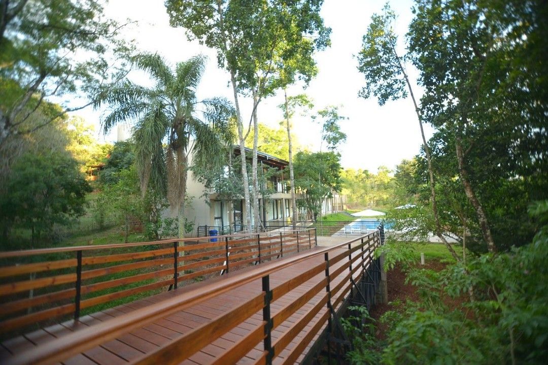 A wooden bridge leading to a house surrounded by trees