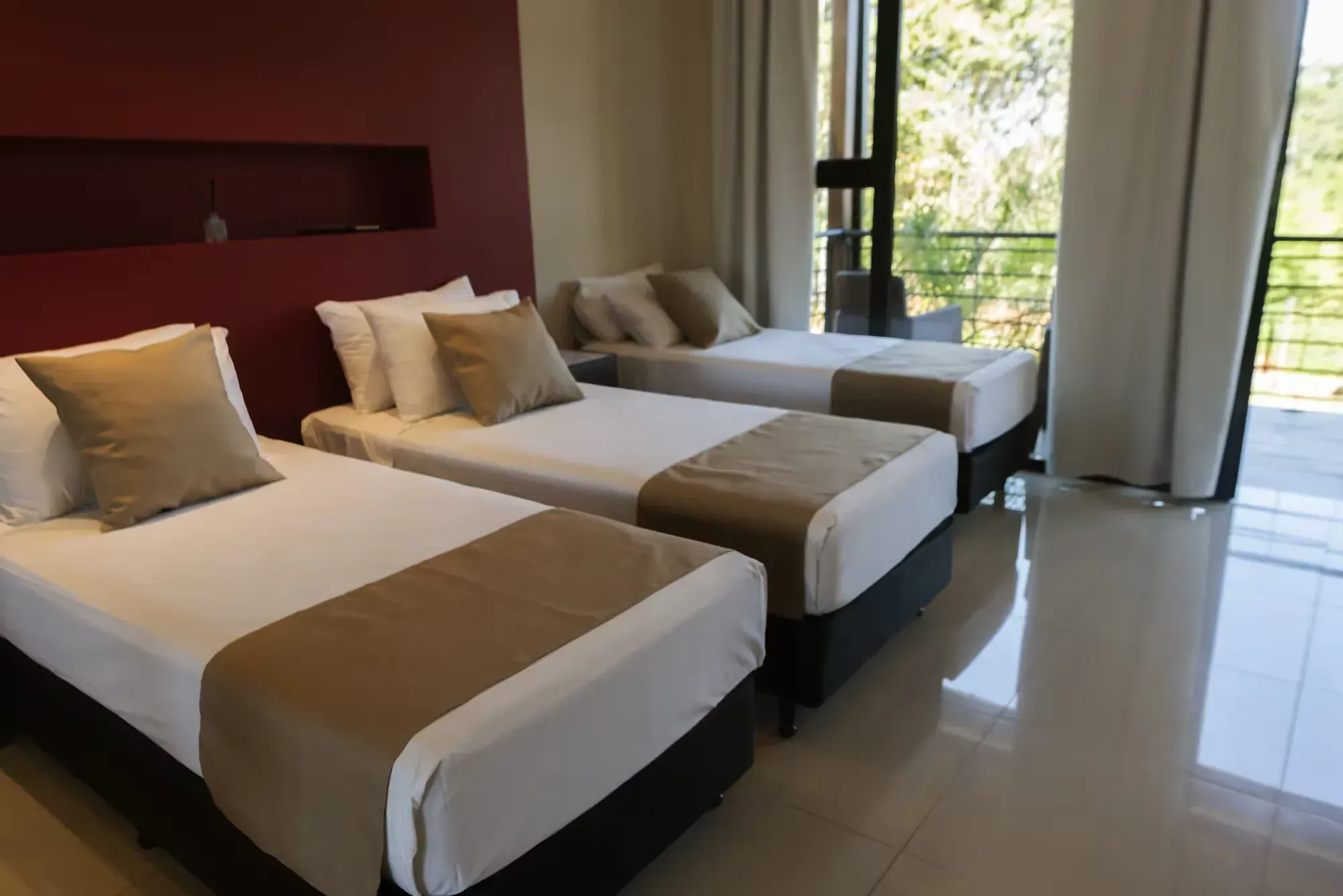 A hotel room with three beds and a balcony