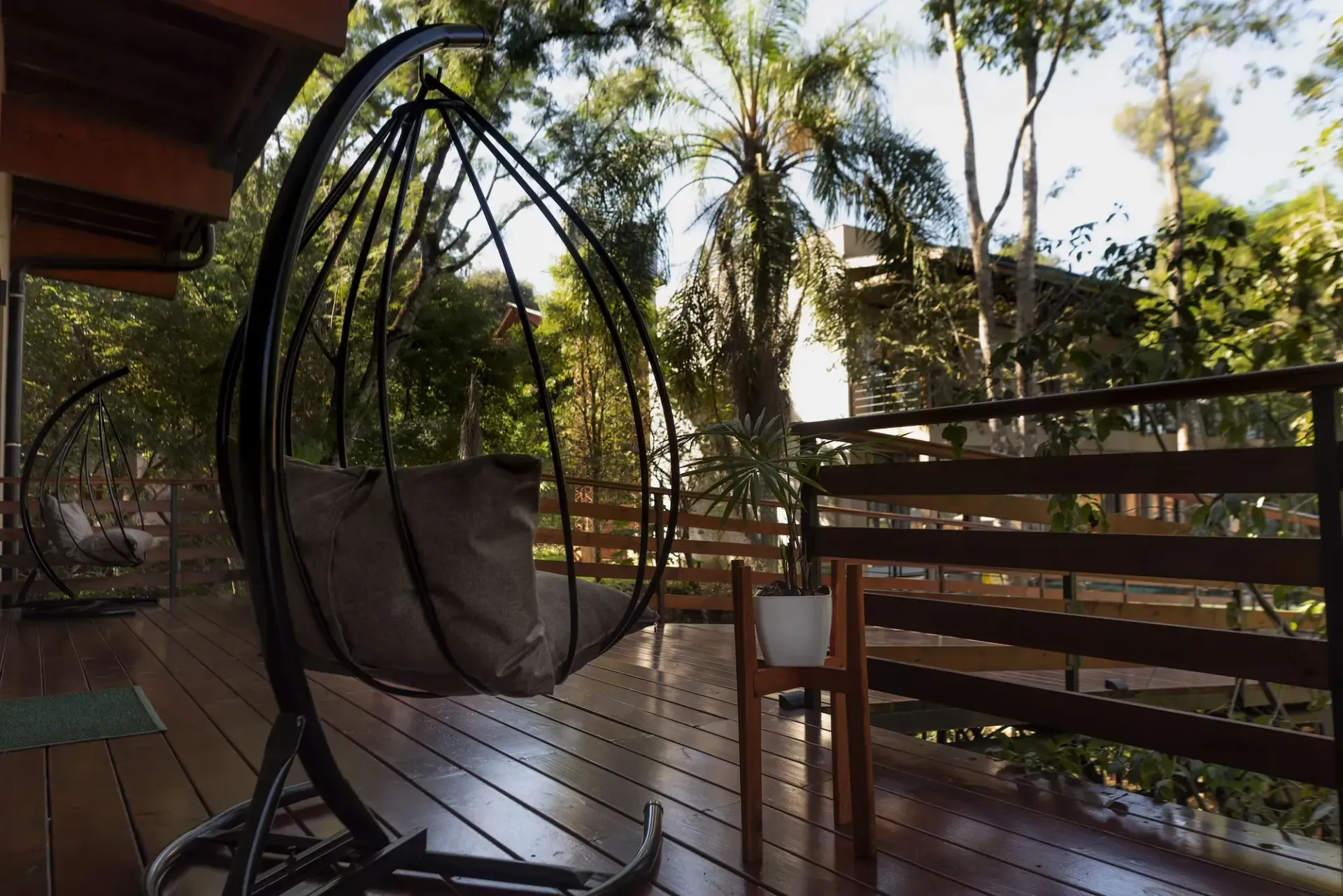 A hanging chair is sitting on a wooden deck.