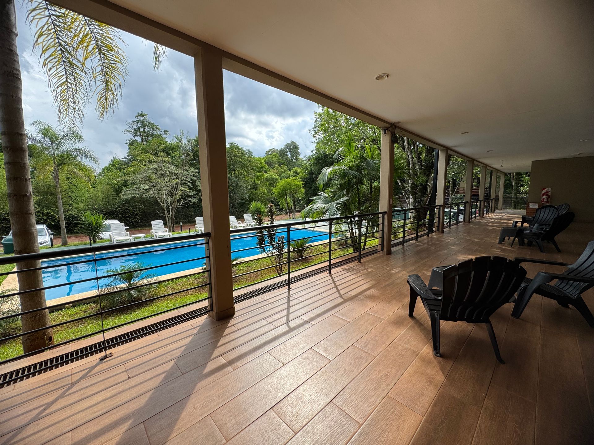 A balcony with chairs and a swimming pool in the background