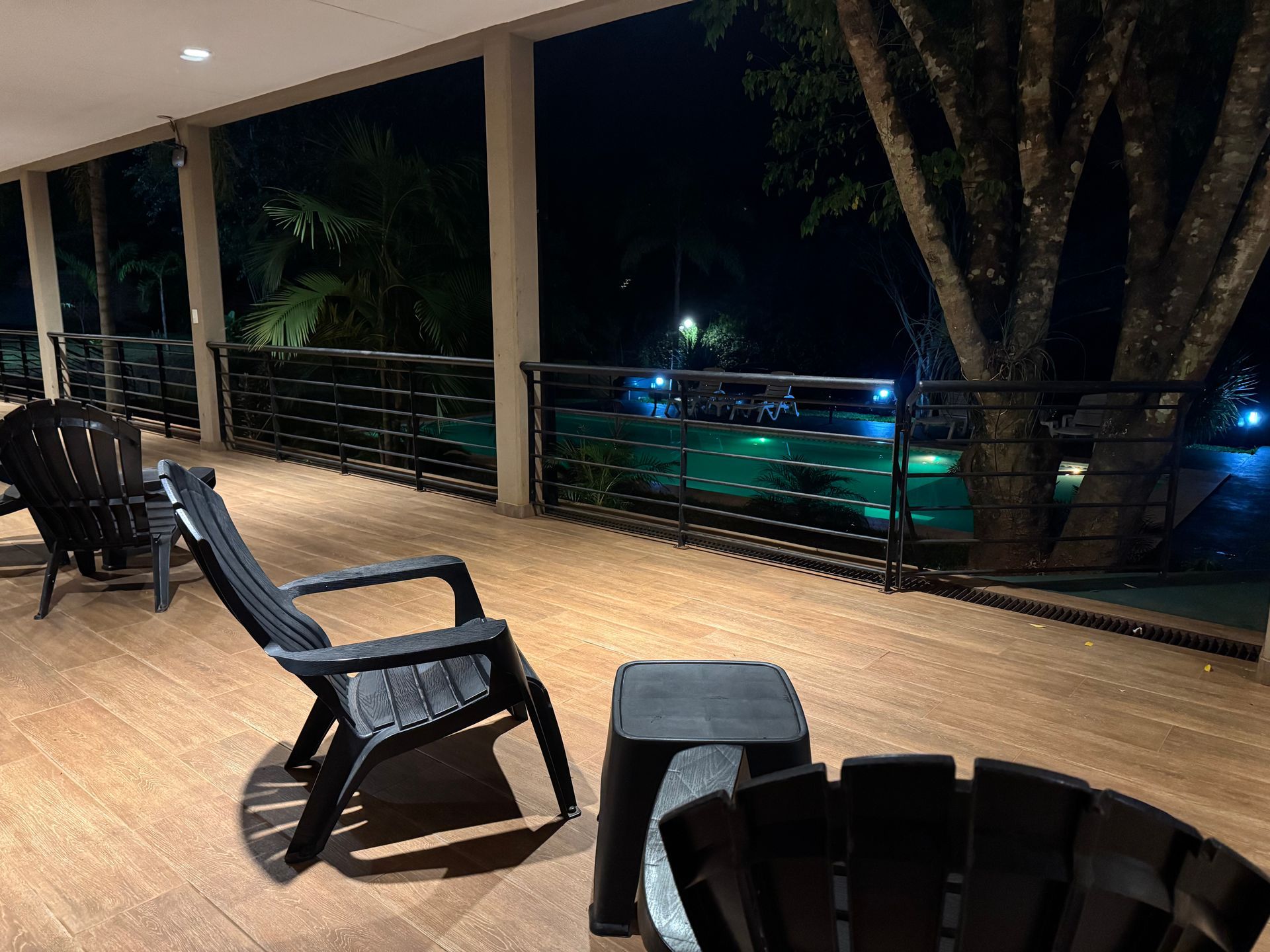 A deck with chairs and a fire pit at night.