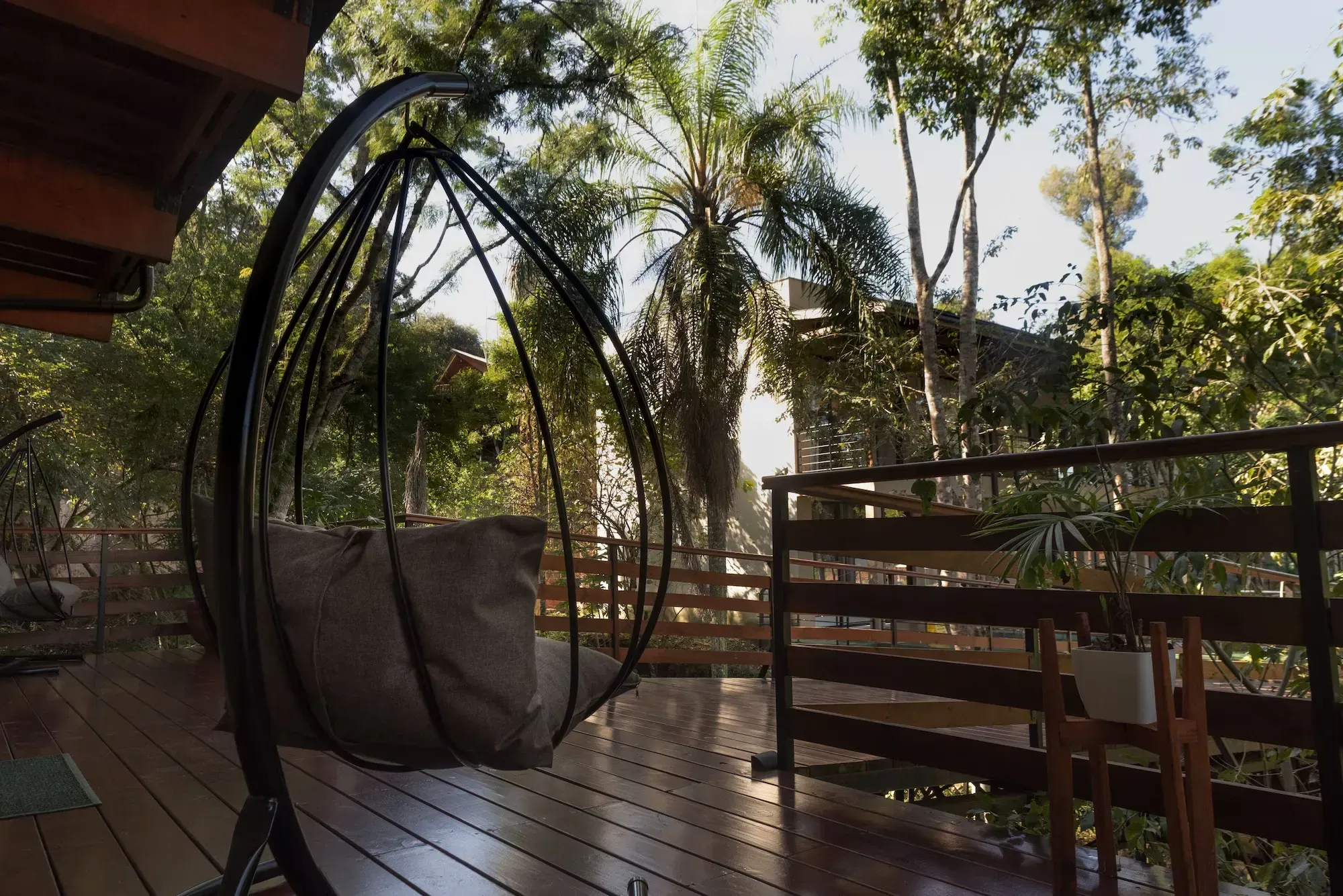 A hanging chair on a wooden deck with trees in the background