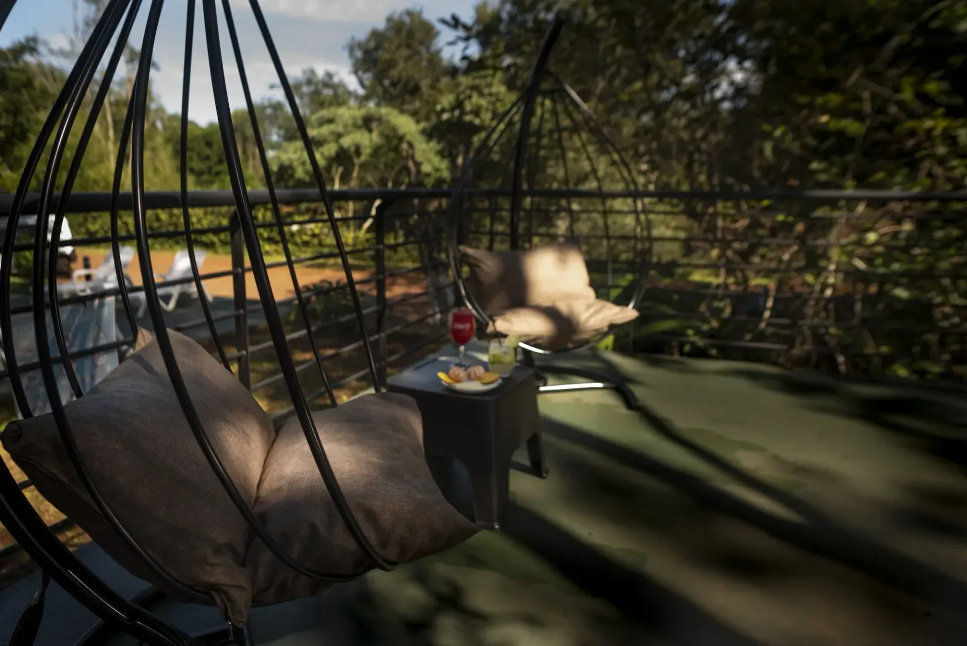 A hanging chair is sitting on a balcony next to a table.