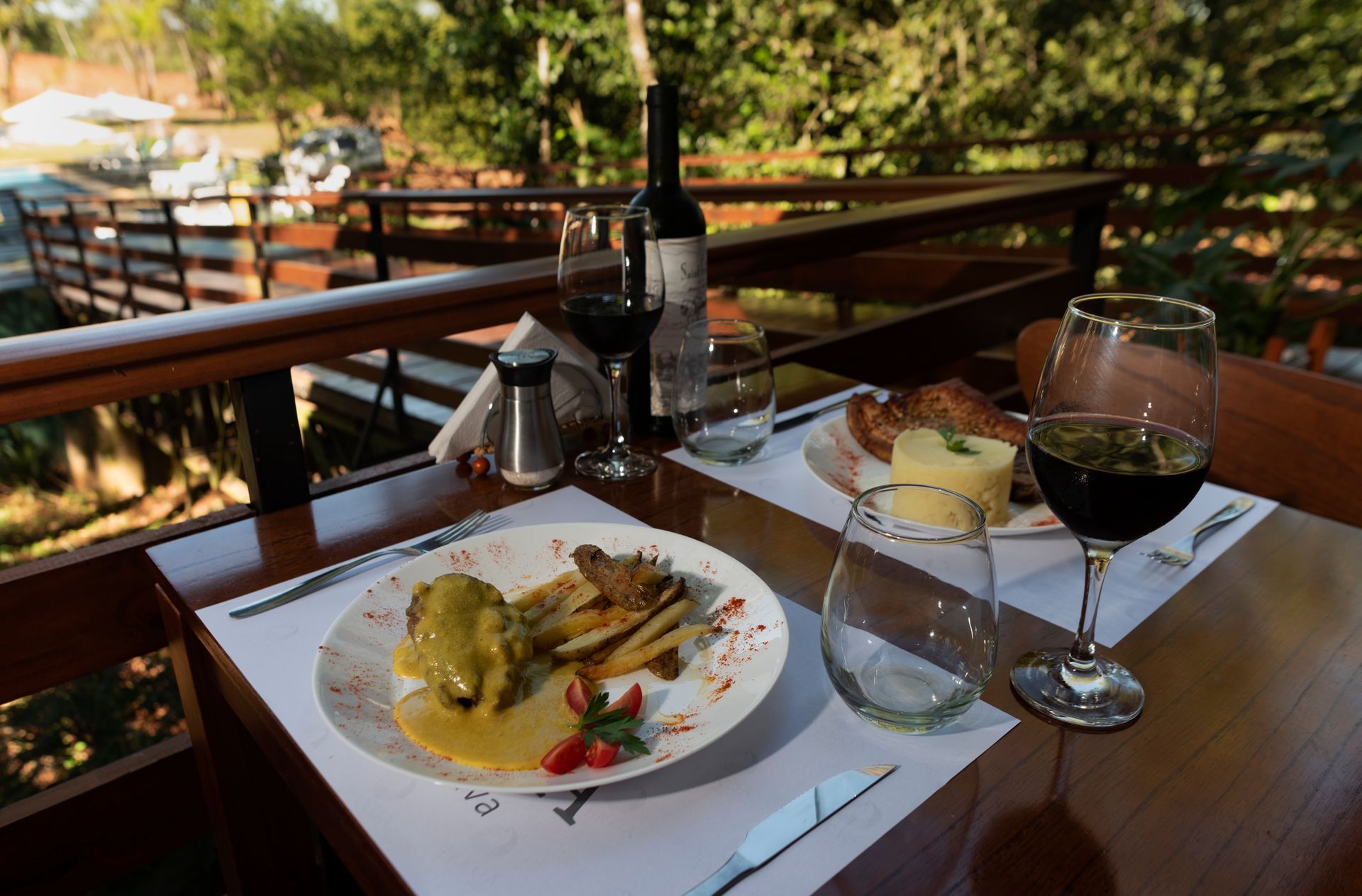 A table with a plate of food and a glass of wine on it.
