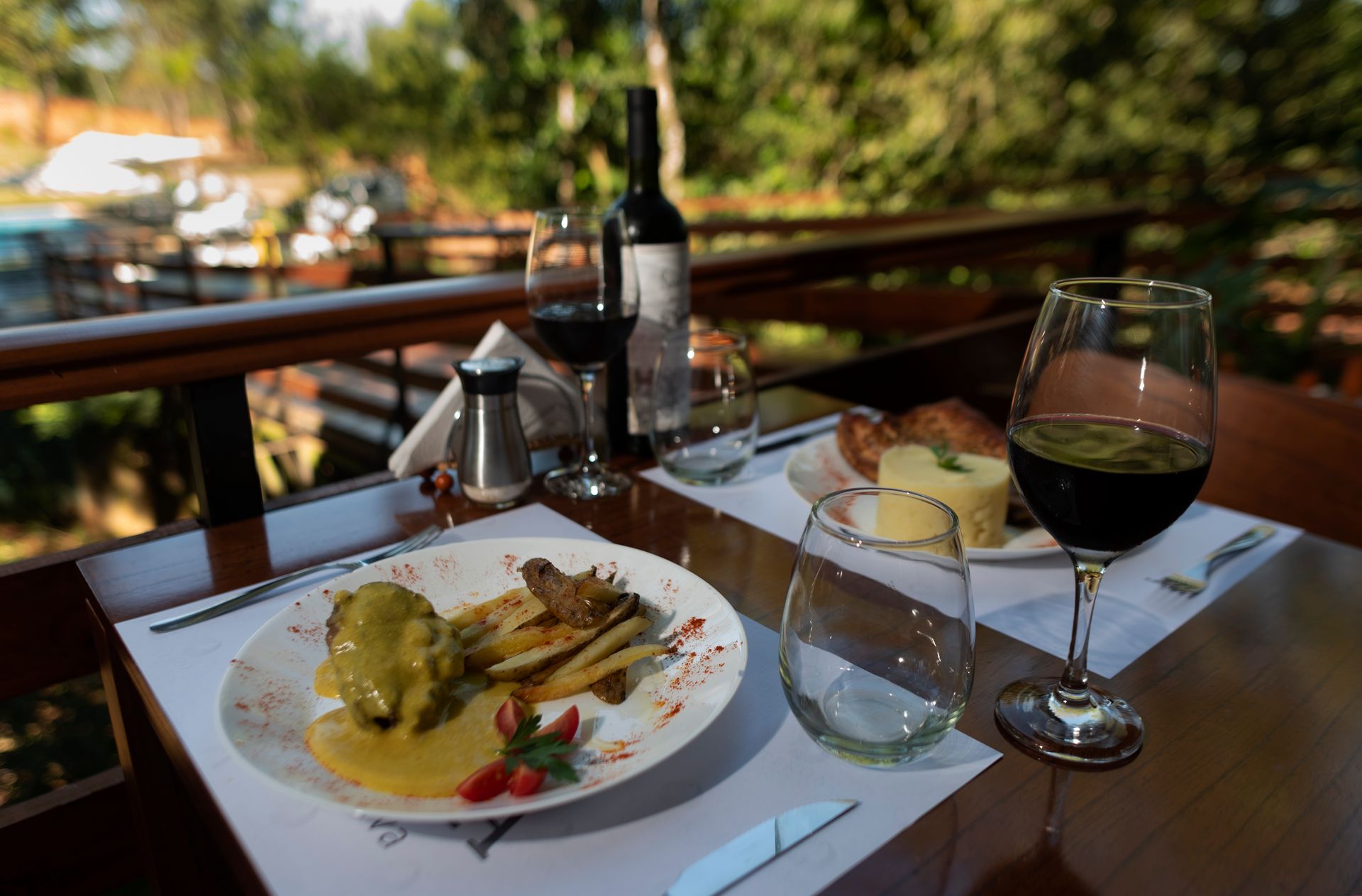 A table with a plate of food and a glass of wine on it.